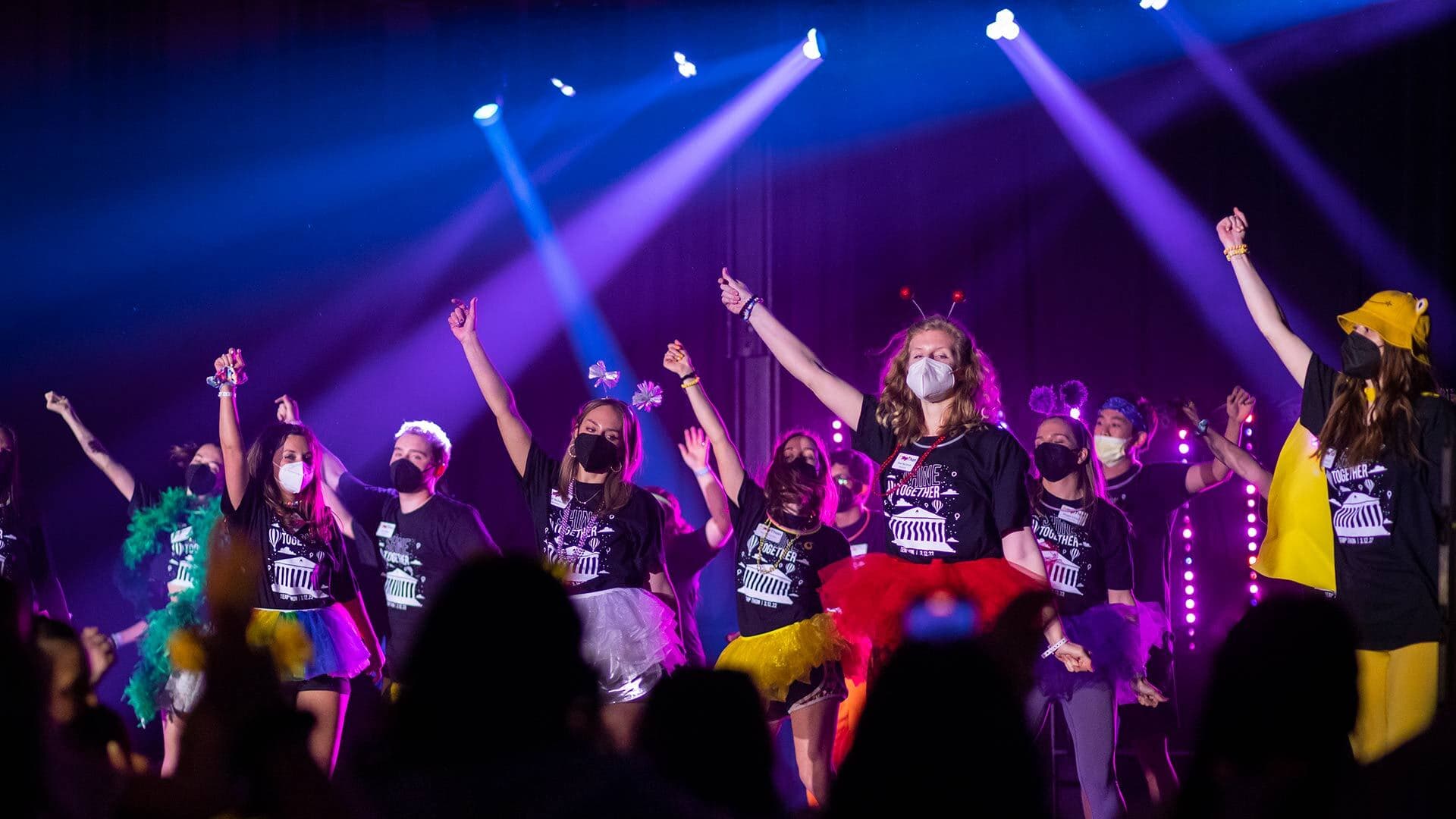 dancers in tutus and event t-shirts on stage vigorously dancing