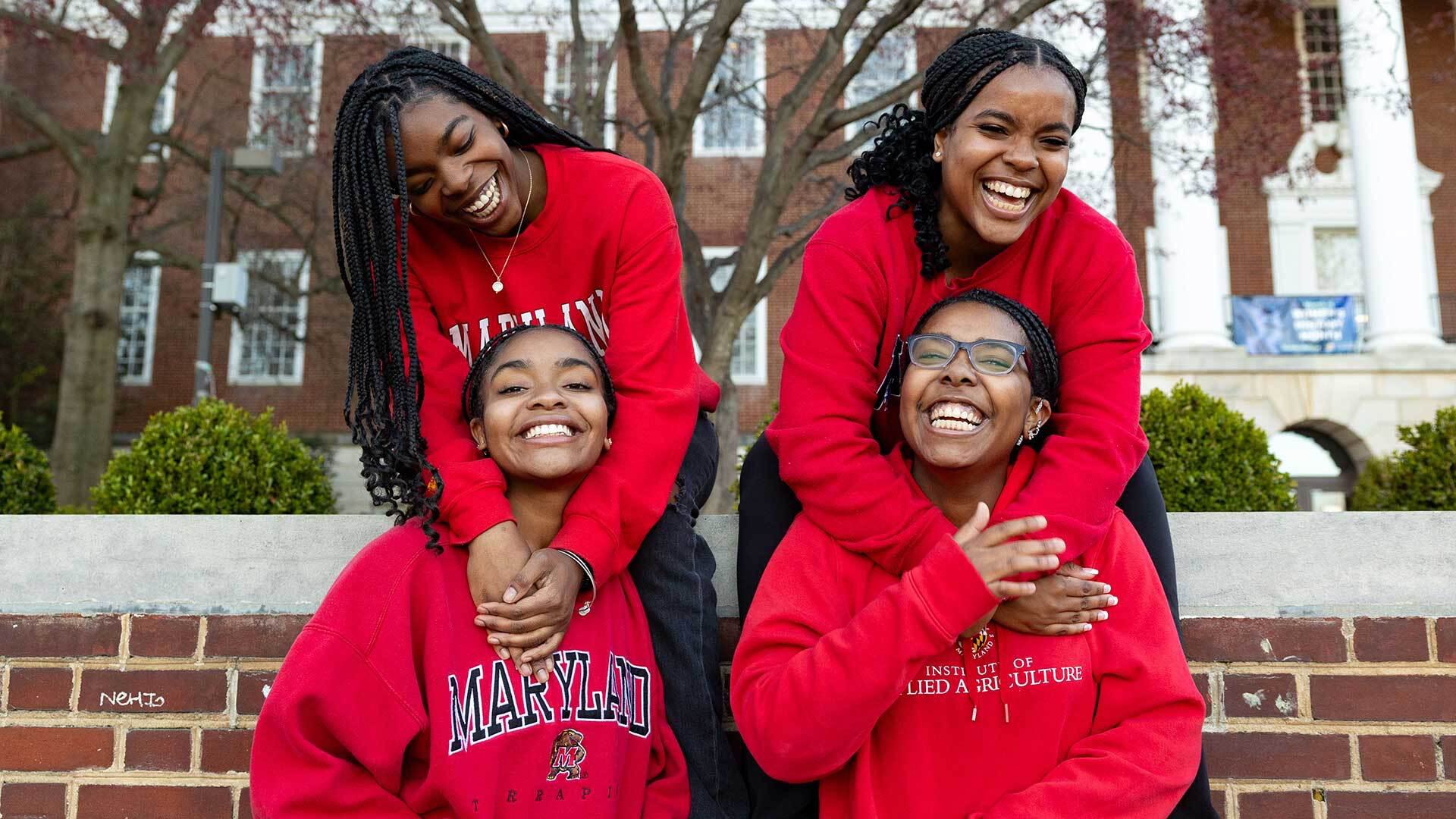 Four Edwards sisters in red Terps gear hugging in pairs