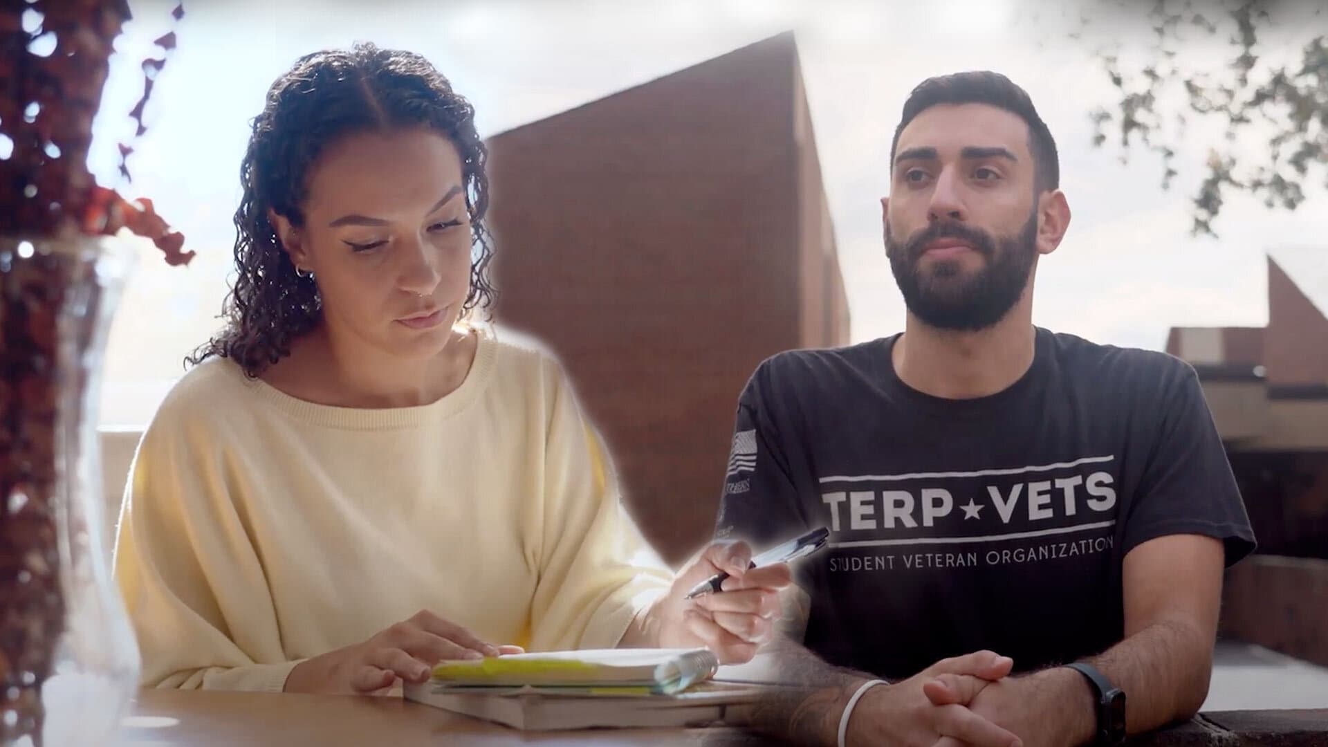 A woman holding a pen writing on a notepad and a man wearing a Terp Vets t-shirt
