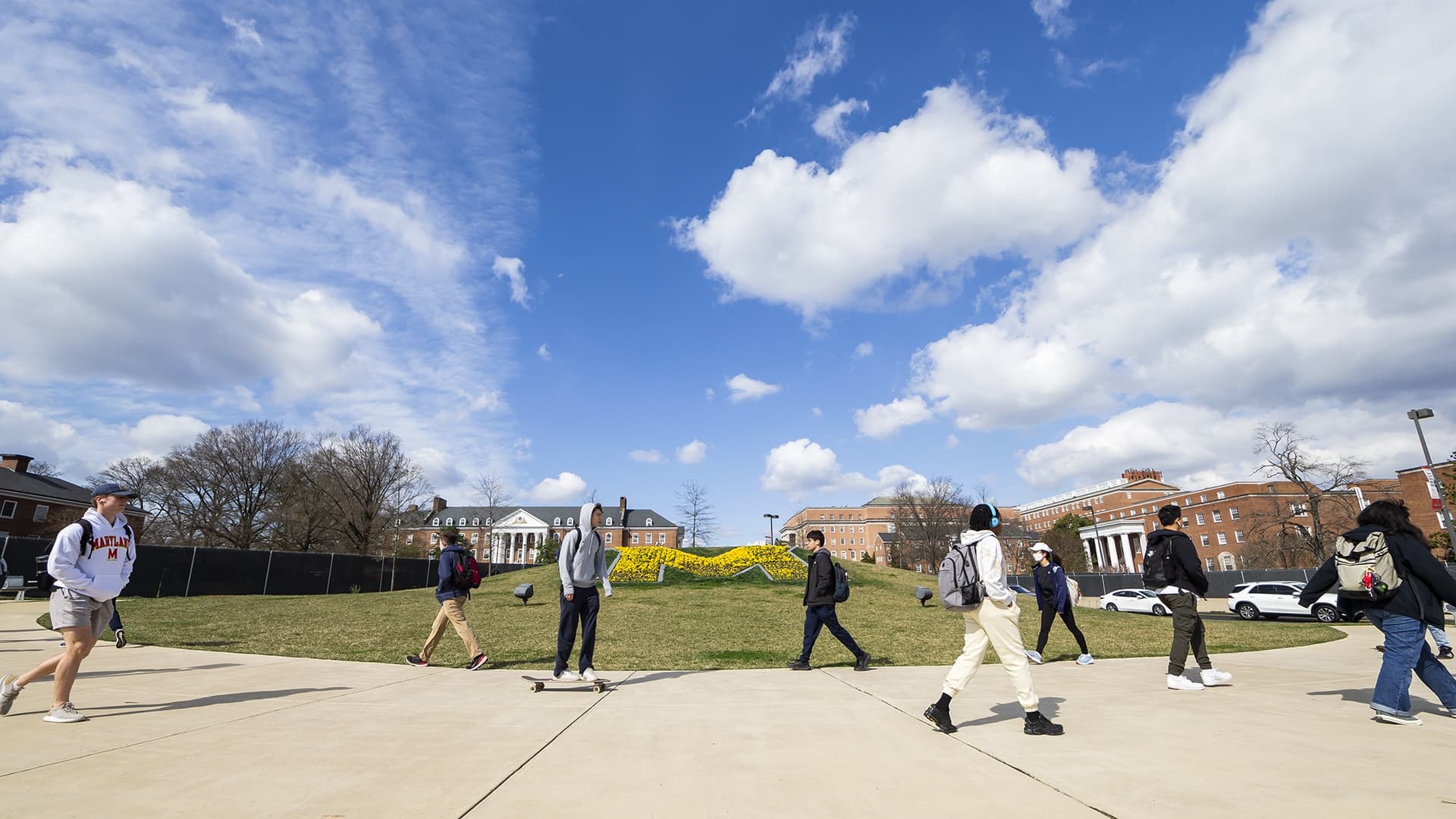 students walk and skateboard past the M on campus