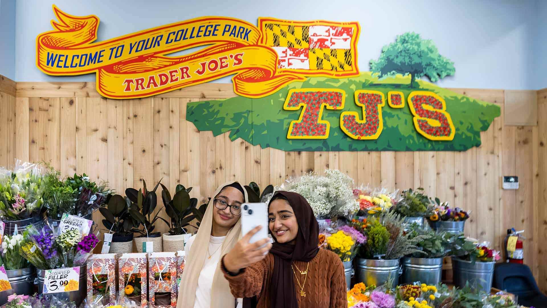 Students take a selfie in front of mural at College Park Trader Joe's