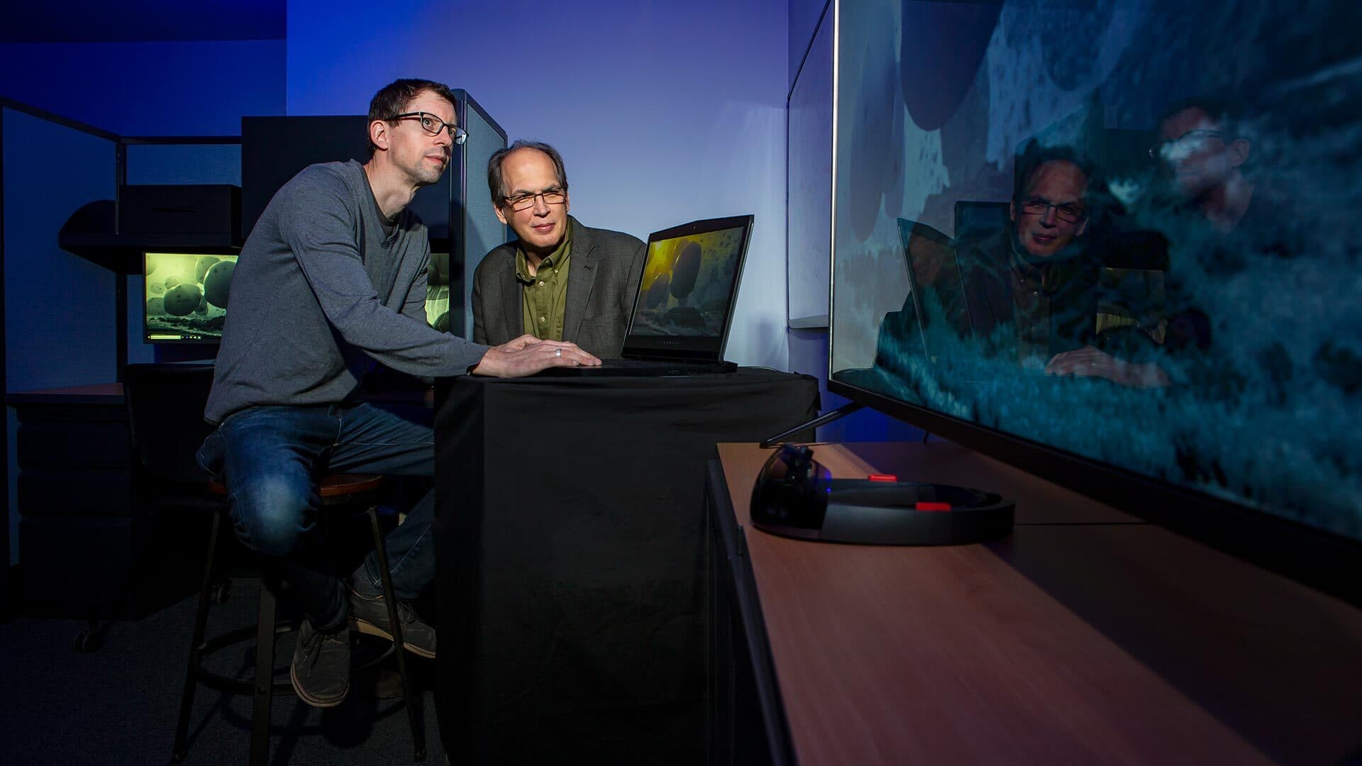 Two men at desk examining computer visualization
