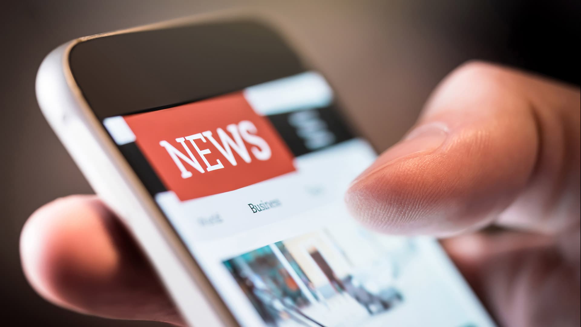 Hand scrolling through news on a smartphone