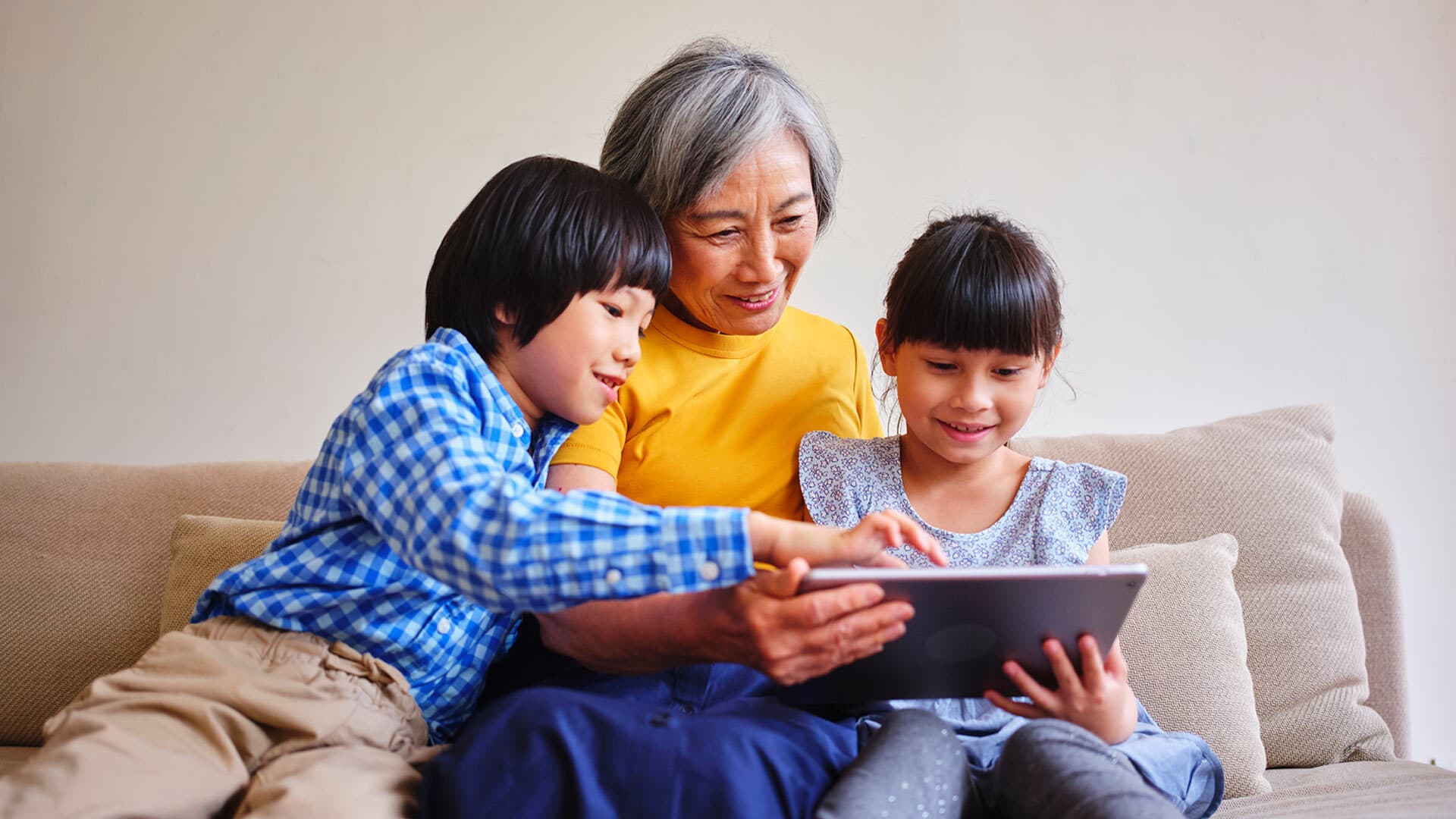 A grandmother looks at a tablet with two children