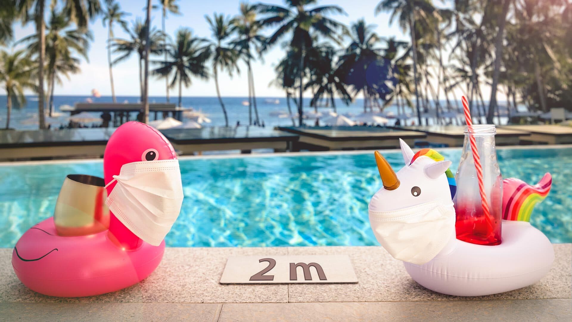 Inflatable flamingo and unicorn wearing face masks near a pool