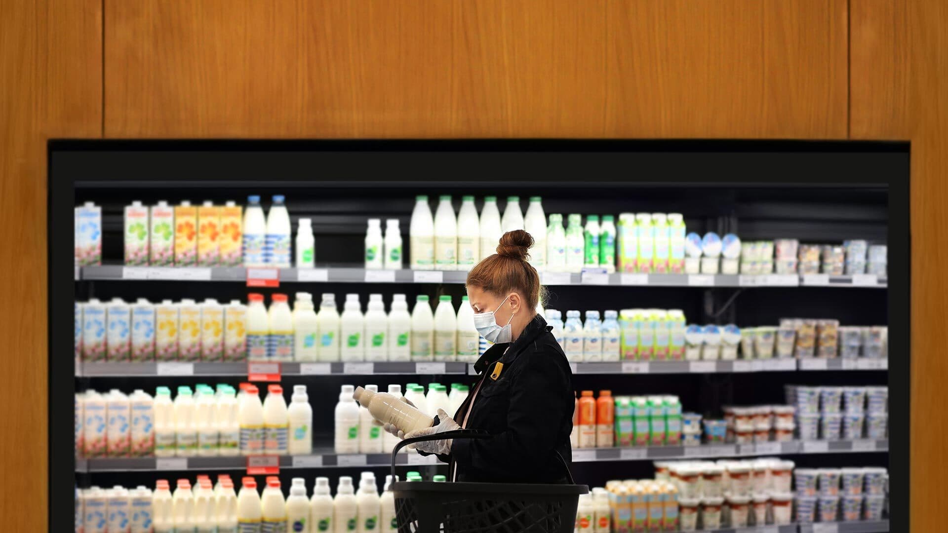 Woman wearing mask shops for milk at grocery store