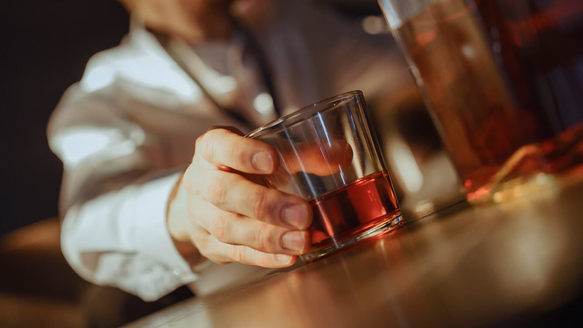 man holding whiskey glass at bar