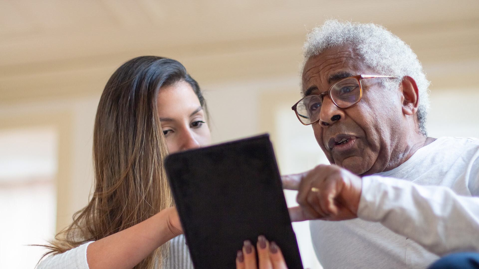 doctor shows older patient tablet