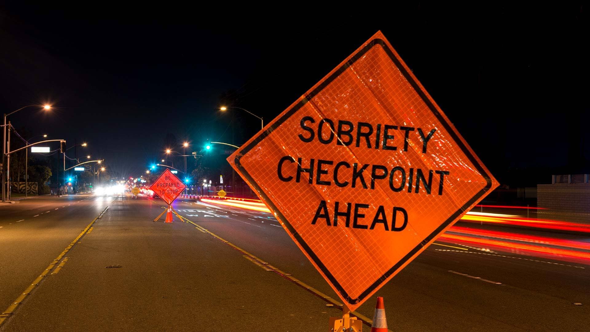 Orange traffic signs that read, "Sobriety Checkpoint Ahead" and "Be Prepared to Stop"