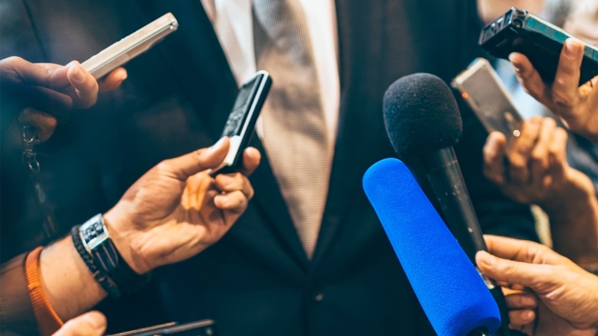 closeup of hands holding recorders and microphones up to interview subject