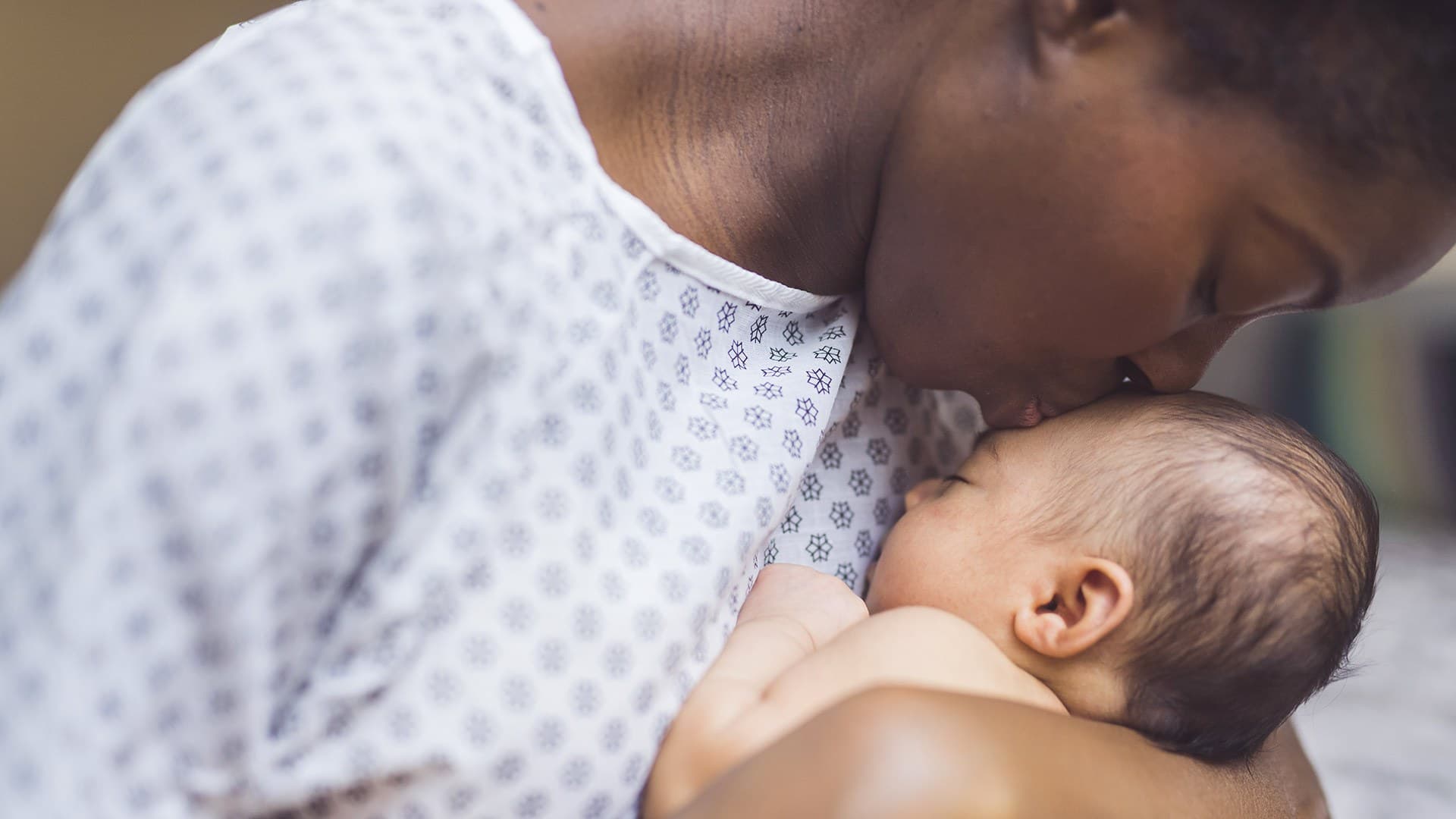 woman kisses newborn on forehead