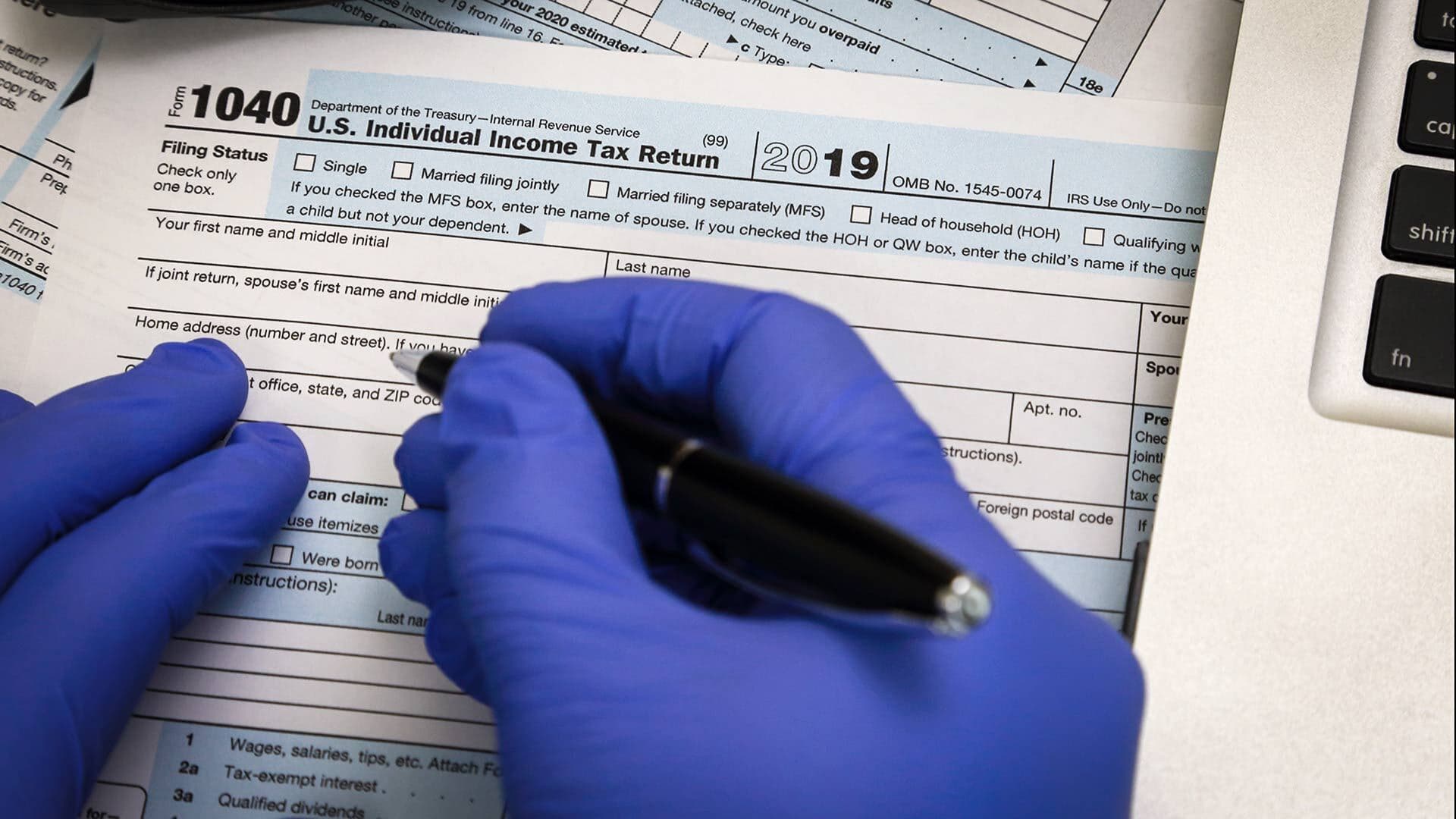 Gloved hands fill out tax form