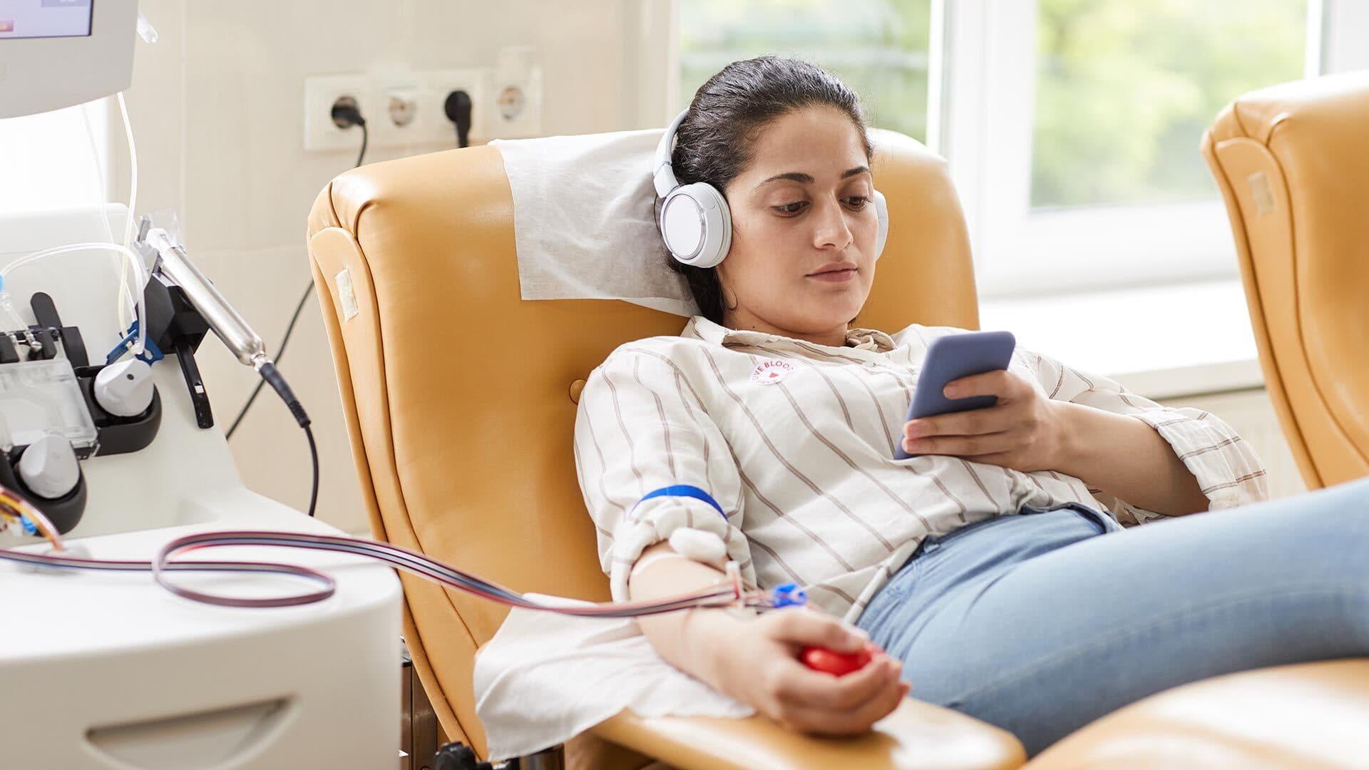 Woman looks at smartphone while giving blood