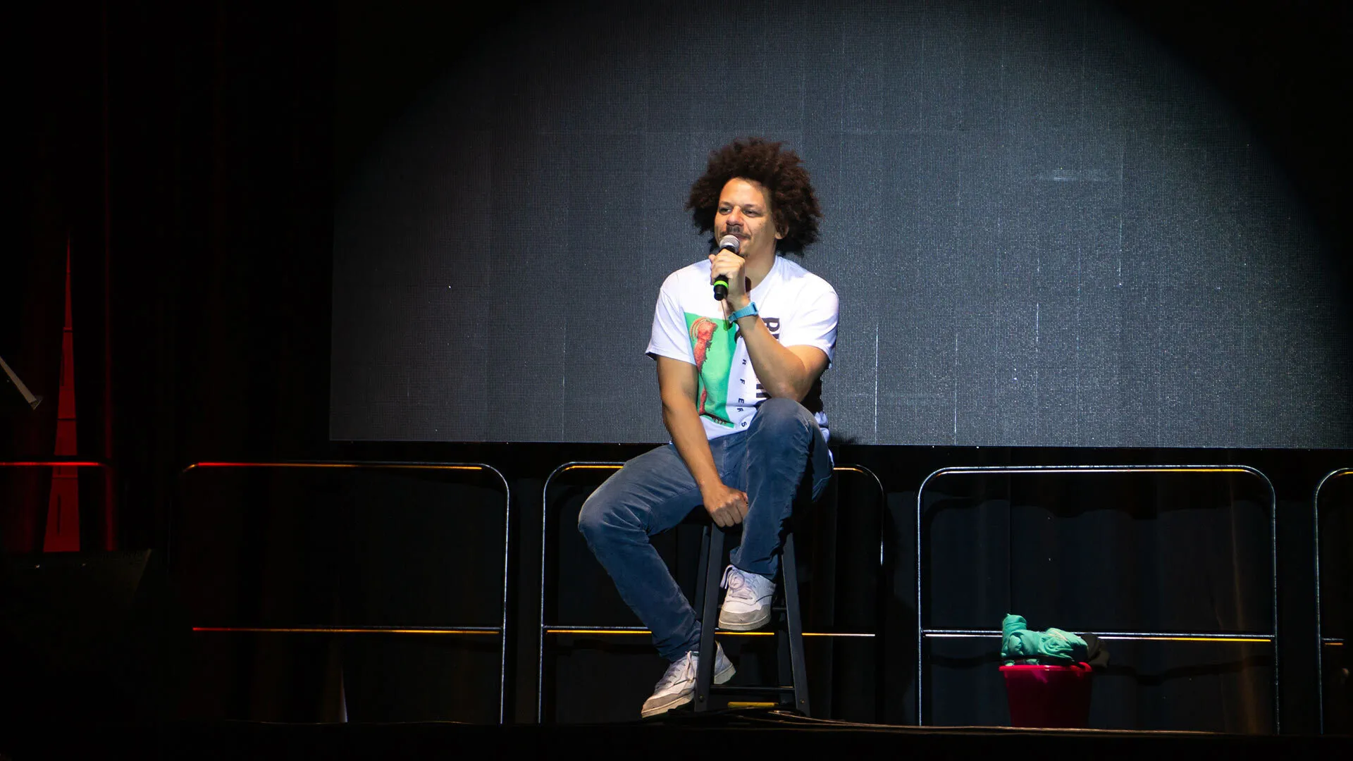 man sits onstage and talks into a mic