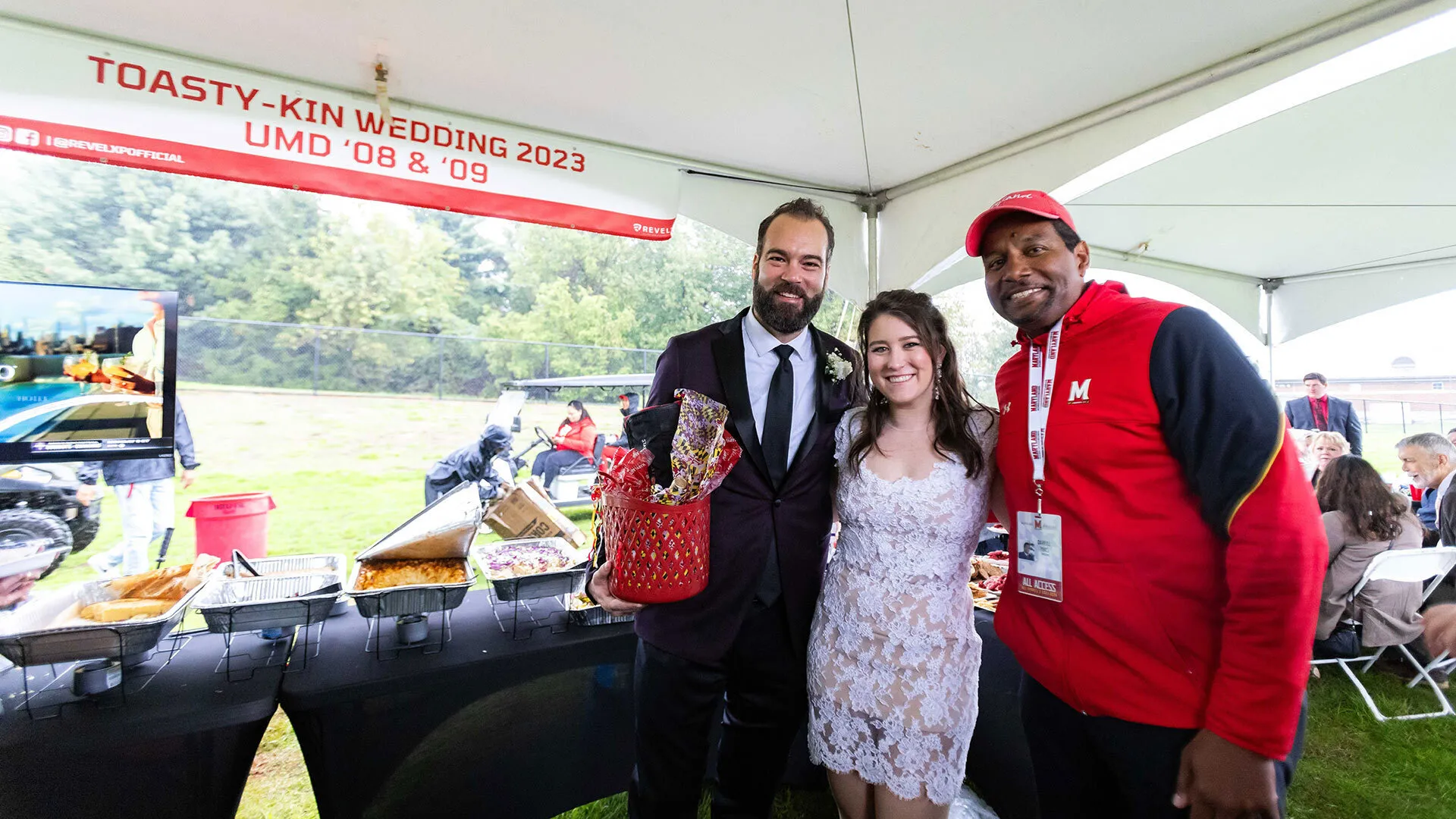 three smiling people pose under a wedding tent