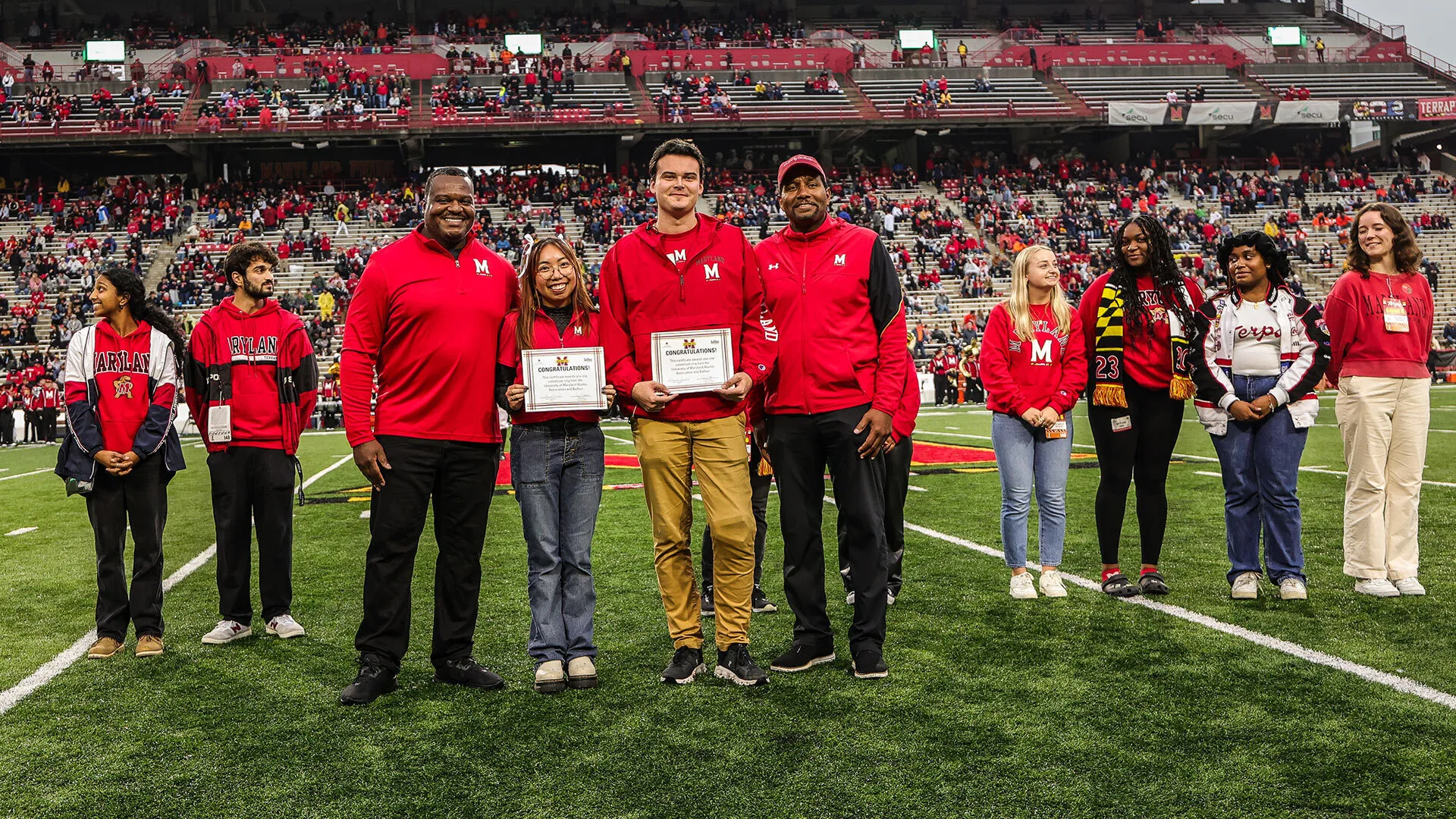 smiling people pose at award ceremony on football field