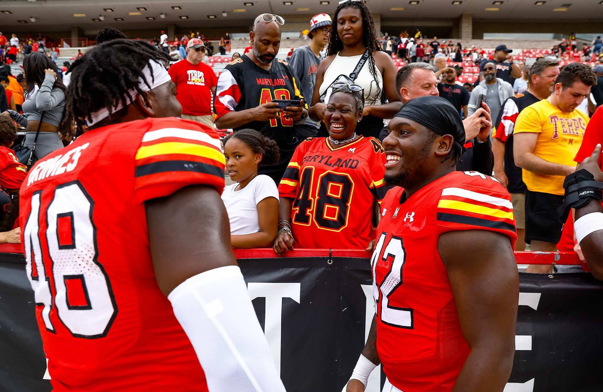 two happy football players interact with people in the stands