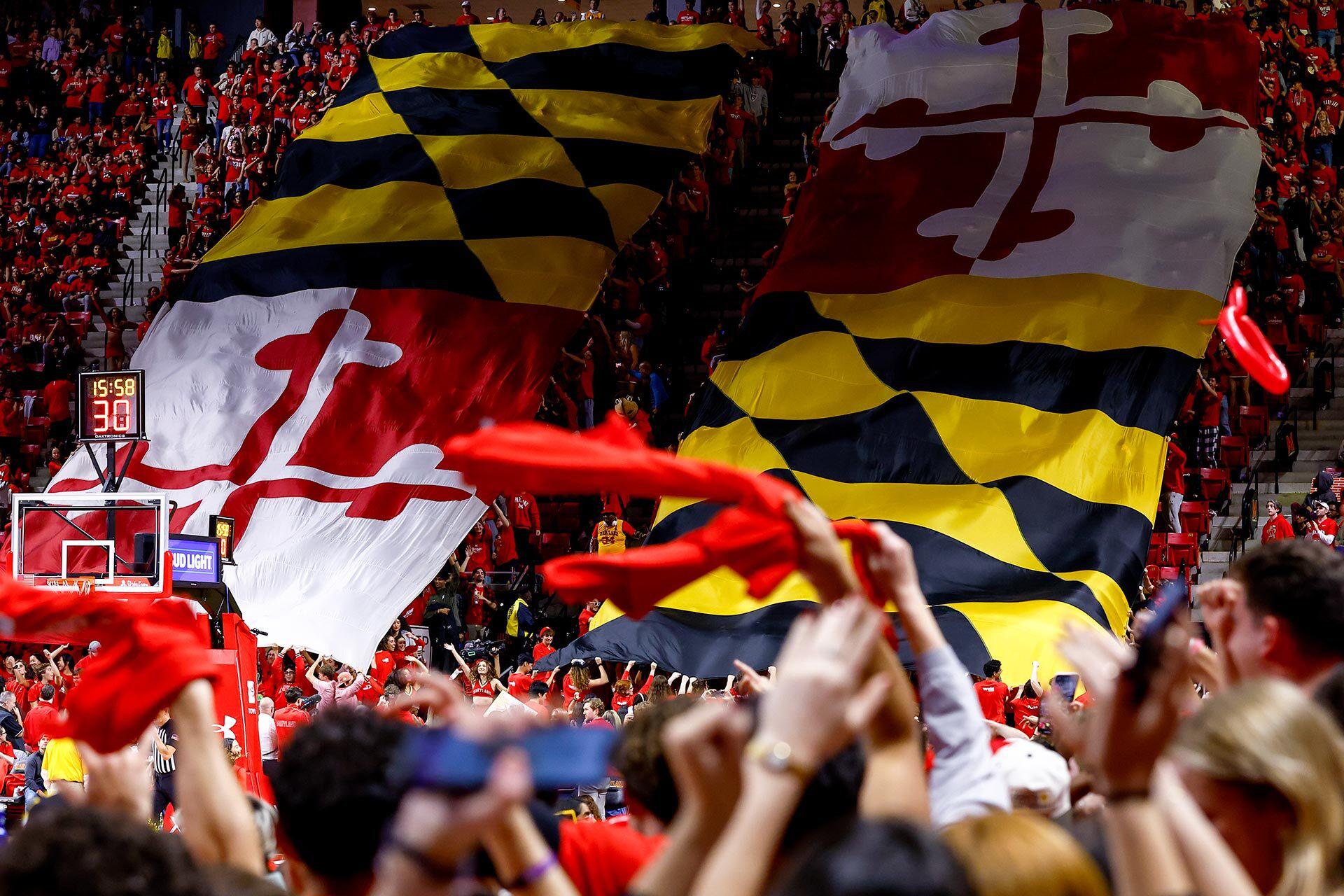 students pull giant Maryland state flag down the stands at a Maryland basketball game