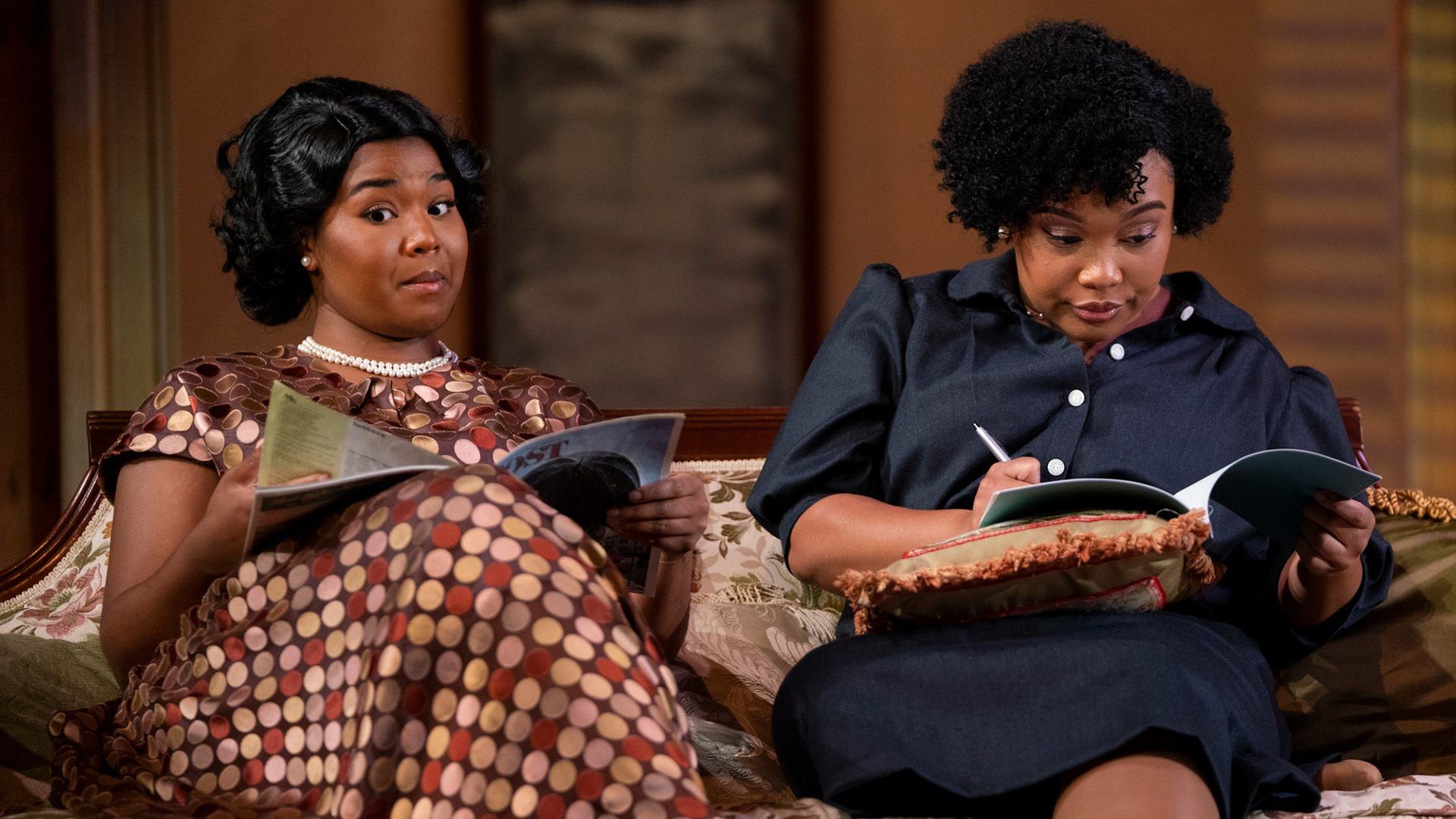 Two Black women look at magazines