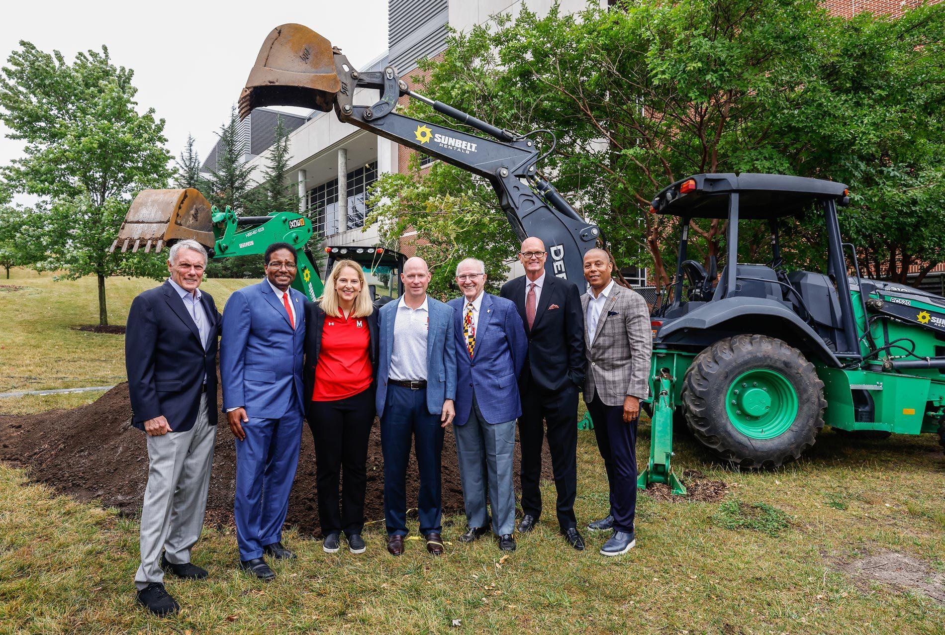 seven people line up in front of excavator