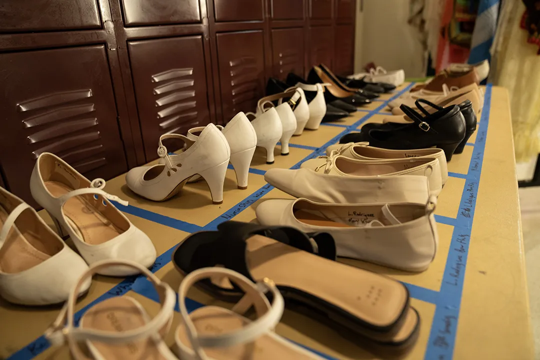 pairs of shoes lined up outside lockers with spaces outlined by blue tape