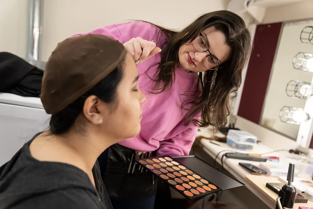 makeup artist applies makeup on performer