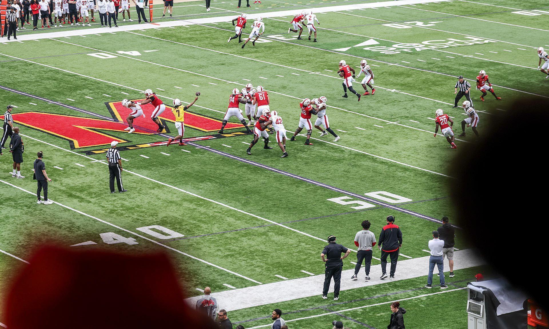a football play proceeds on a field with a giant M