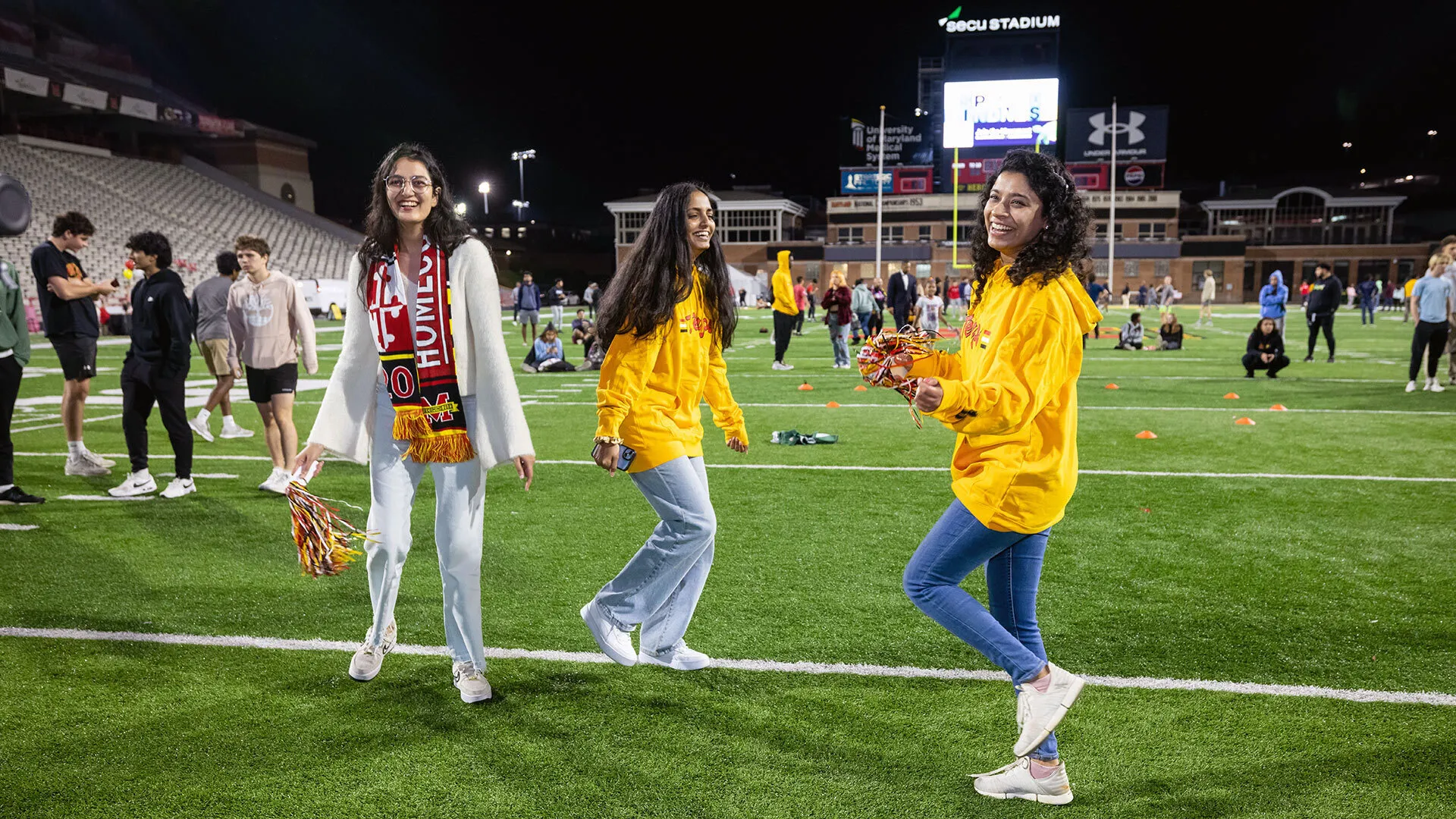 three women stand together on a football field
