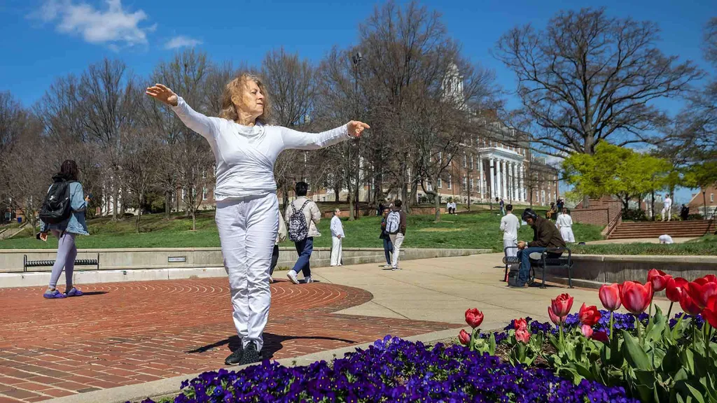 Woman poses with arms outstretched near flowers