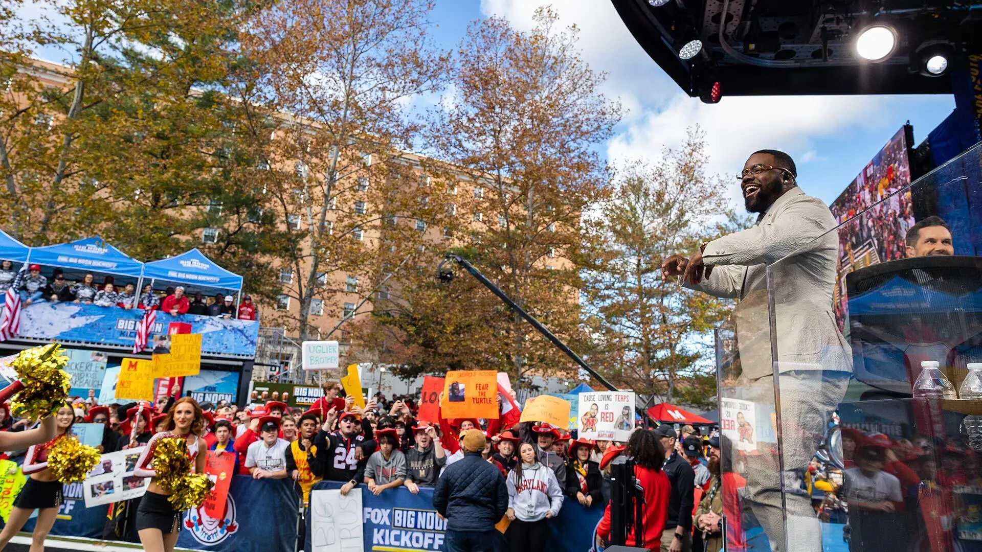 man looks out over a crowd that includes Maryland cheerleaders