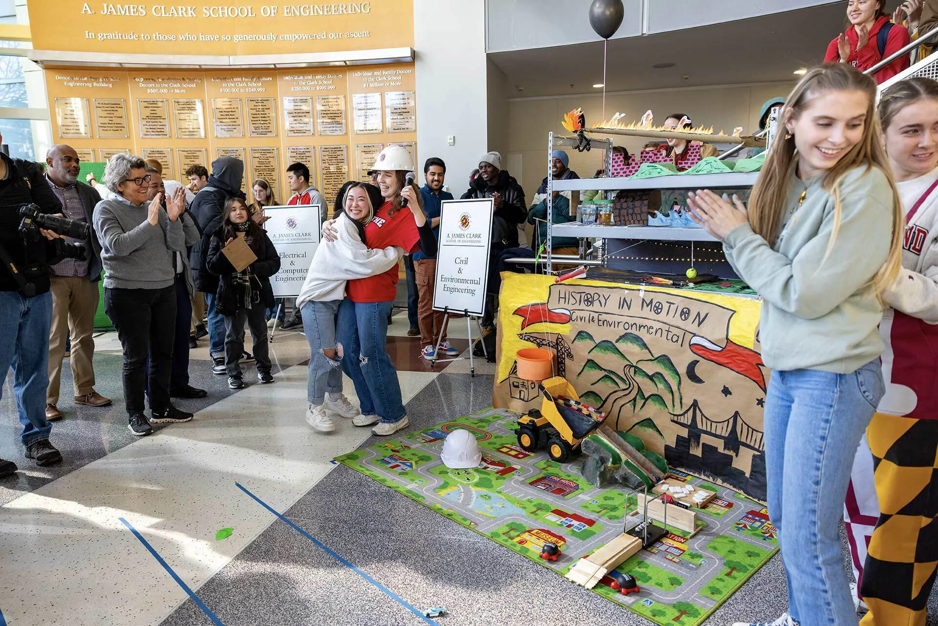 students hug in front of their Rube Goldberg machine