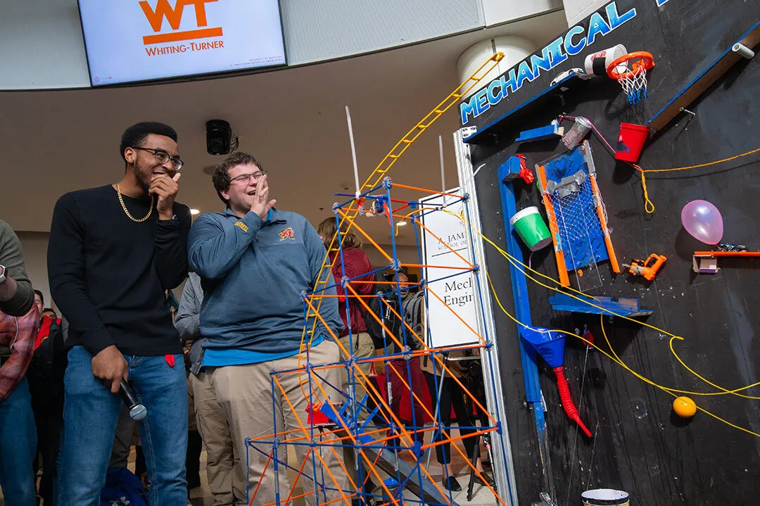 two students laugh looking at their rube goldberg machine