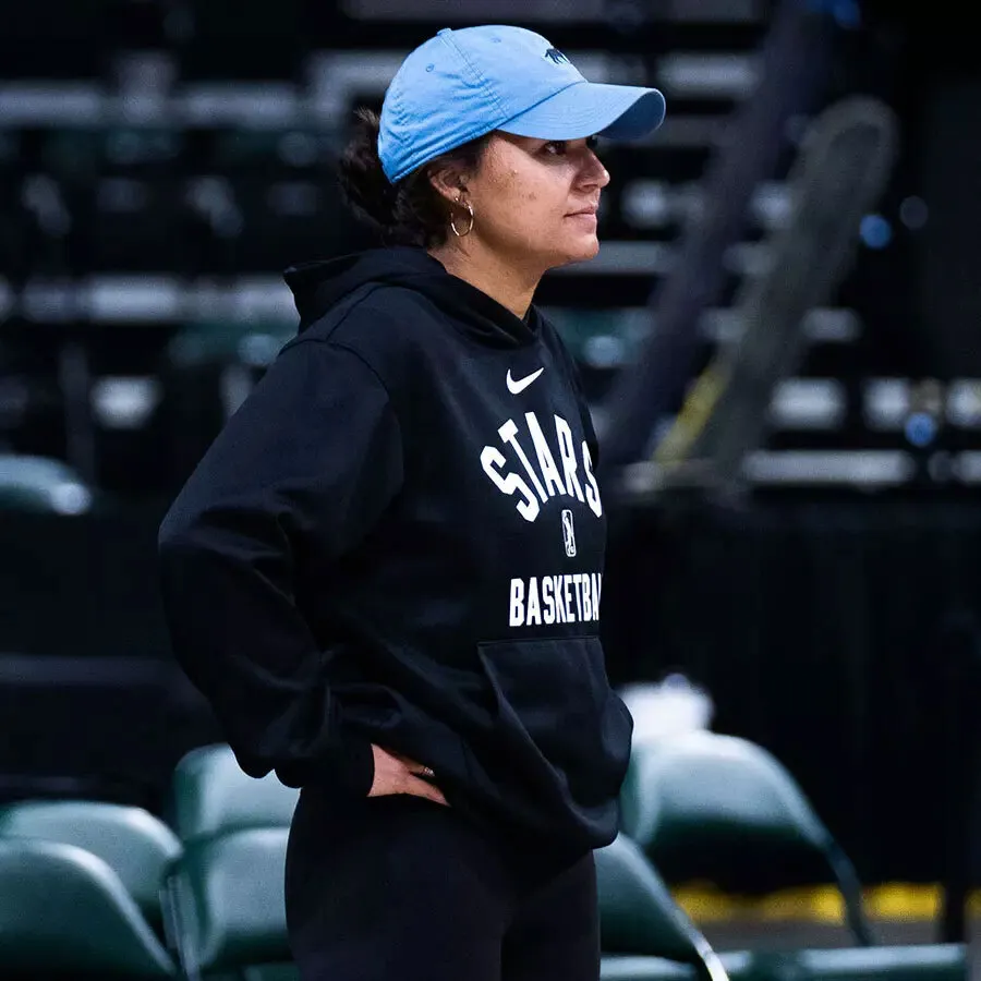 Katie Benzan with hands on hips, wearing blue hat and black Stars hoodie