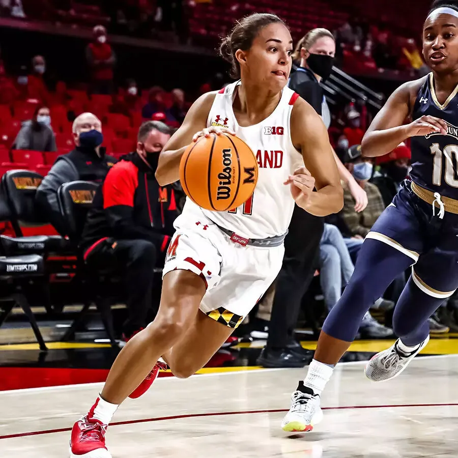 Katie Benzan dribbles basketball with UMD jersey