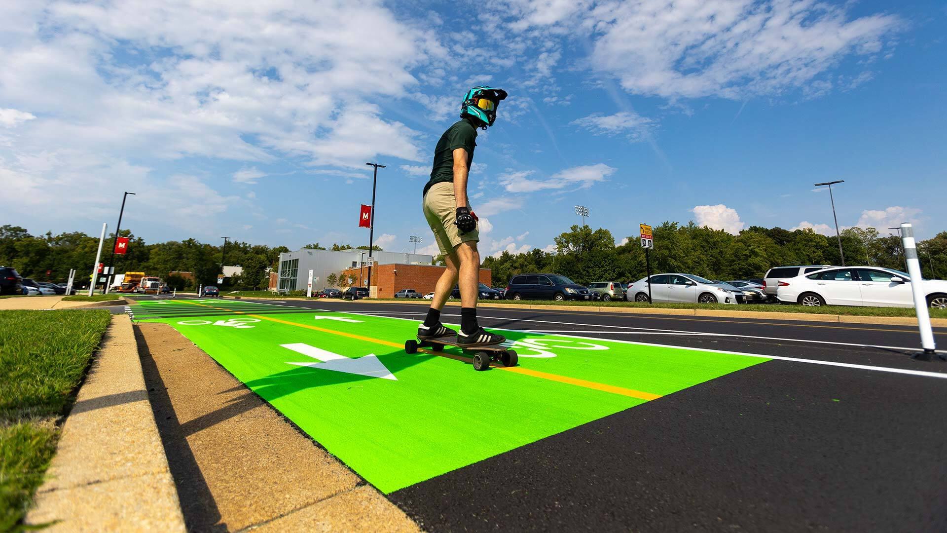 A skateboarder rides in newly painted green bike lane
