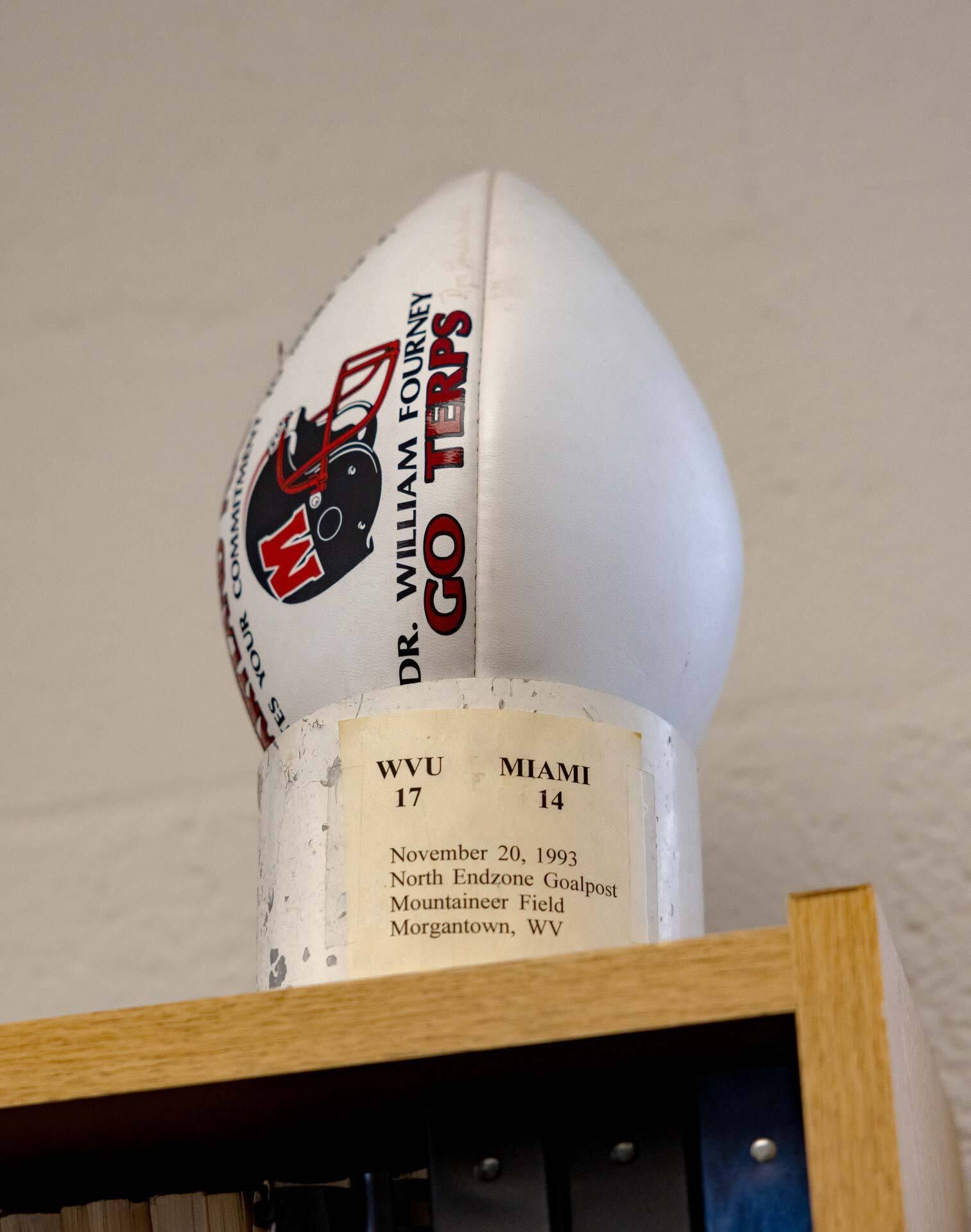 football with Go Terps and Dr. Bill Fourney written on it sitting in a piece of white goal post