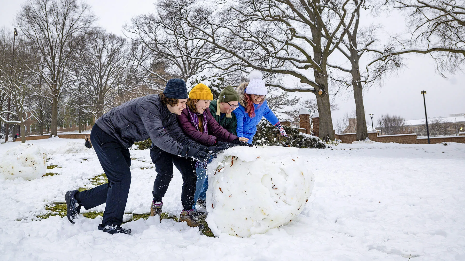 three students roll up a giant snowball