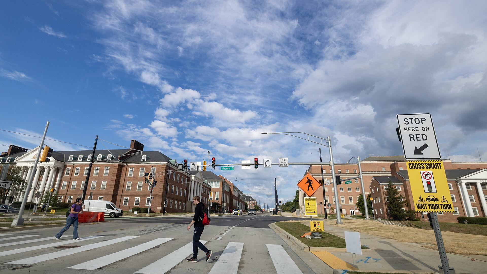 students cross street at crosswalk at new stoplight at Regents Drive