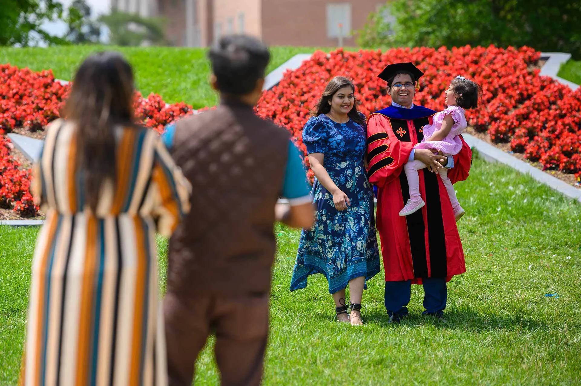 graduate poses with his family in front of the M