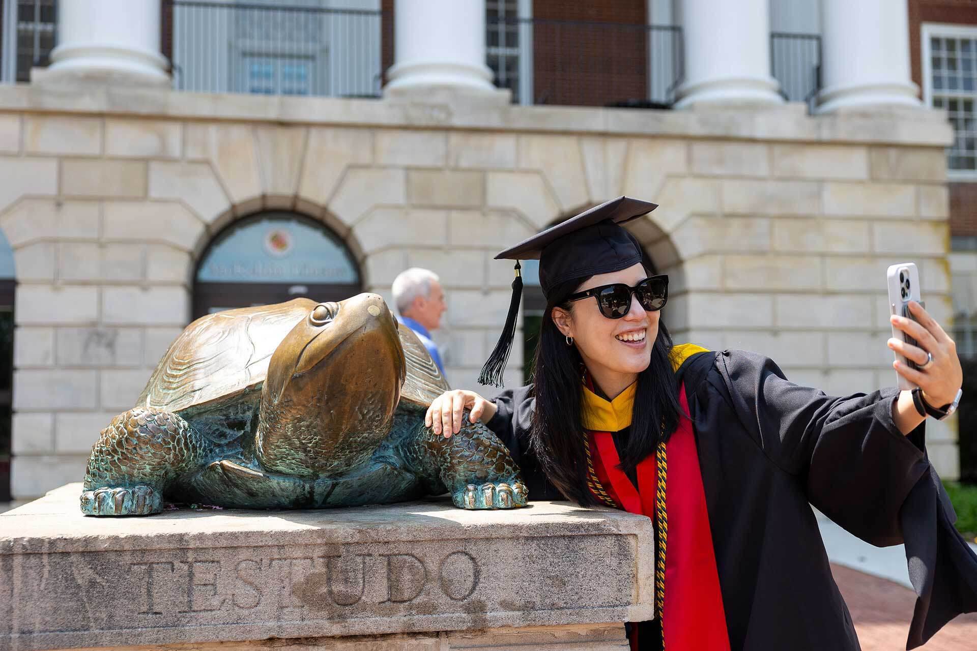 graduate takes selfie with Testudo statue