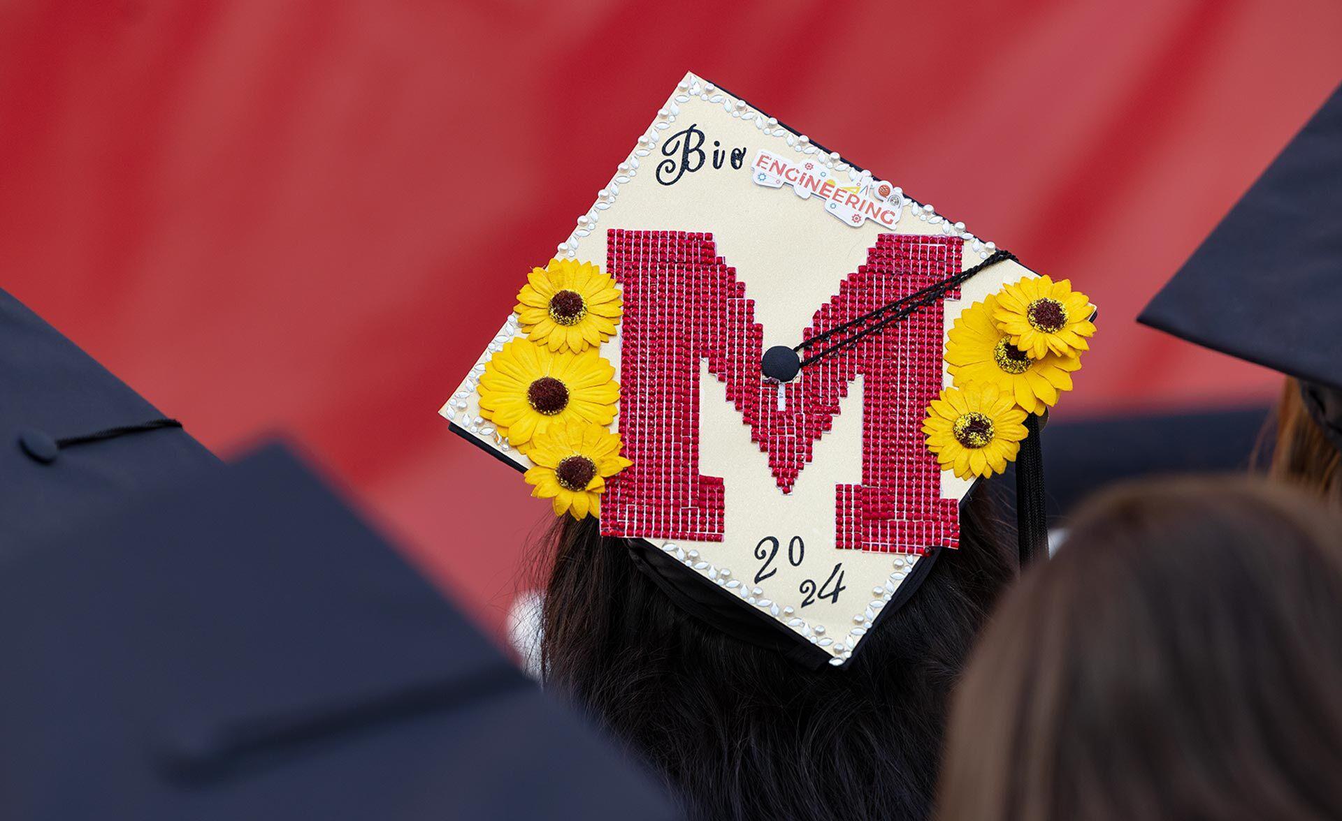 personalized mortarboard with red M and yellow flowers