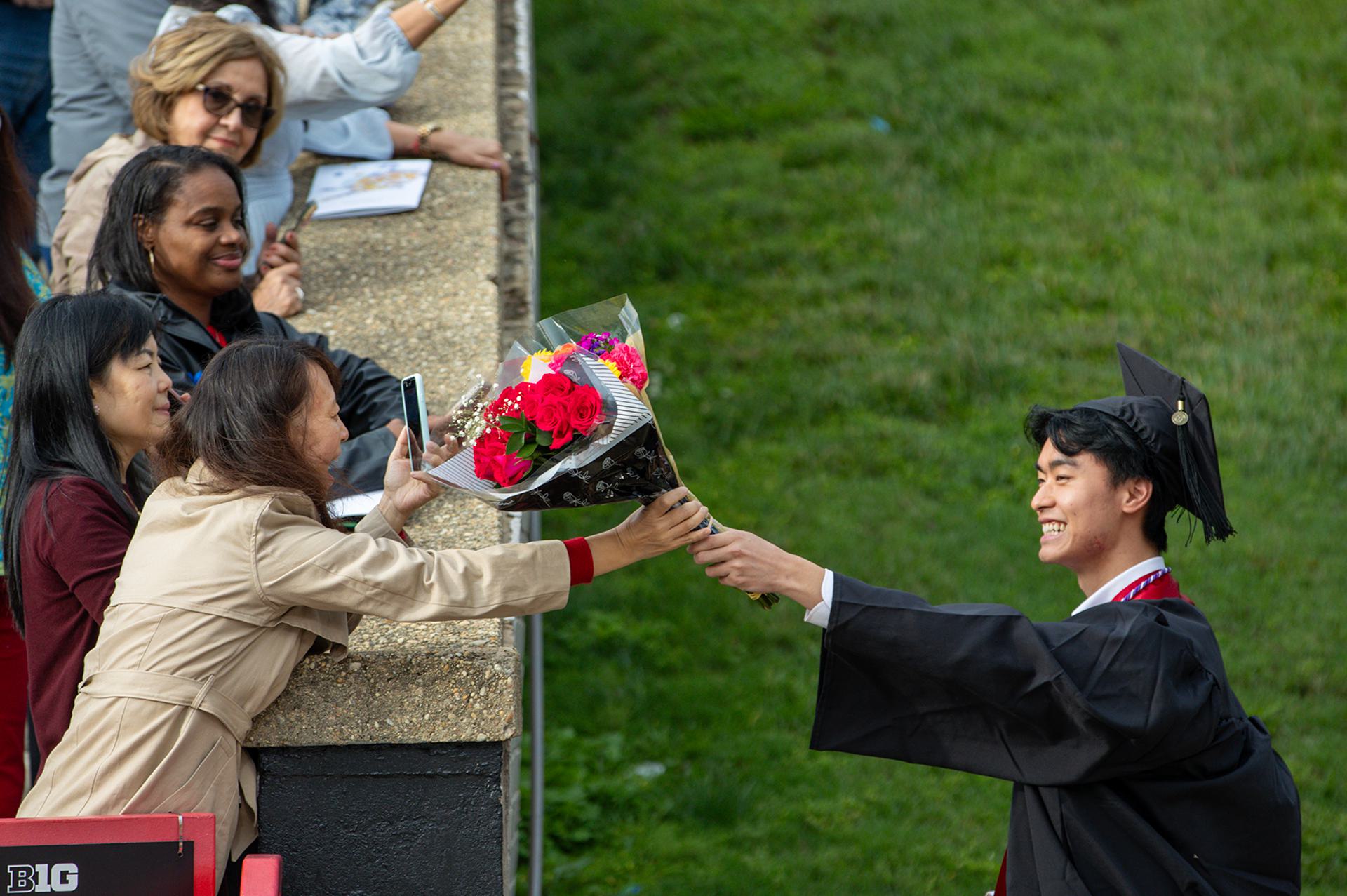 student hands flowers to mom