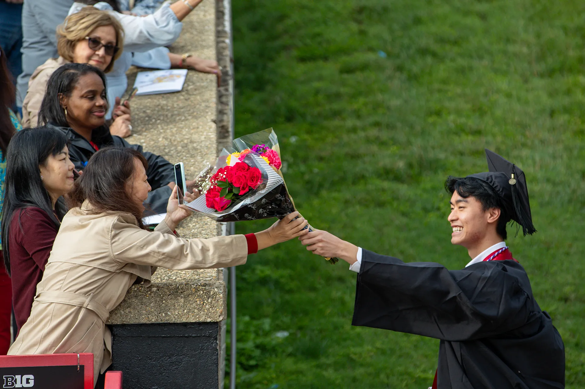 student hands flowers to mom
