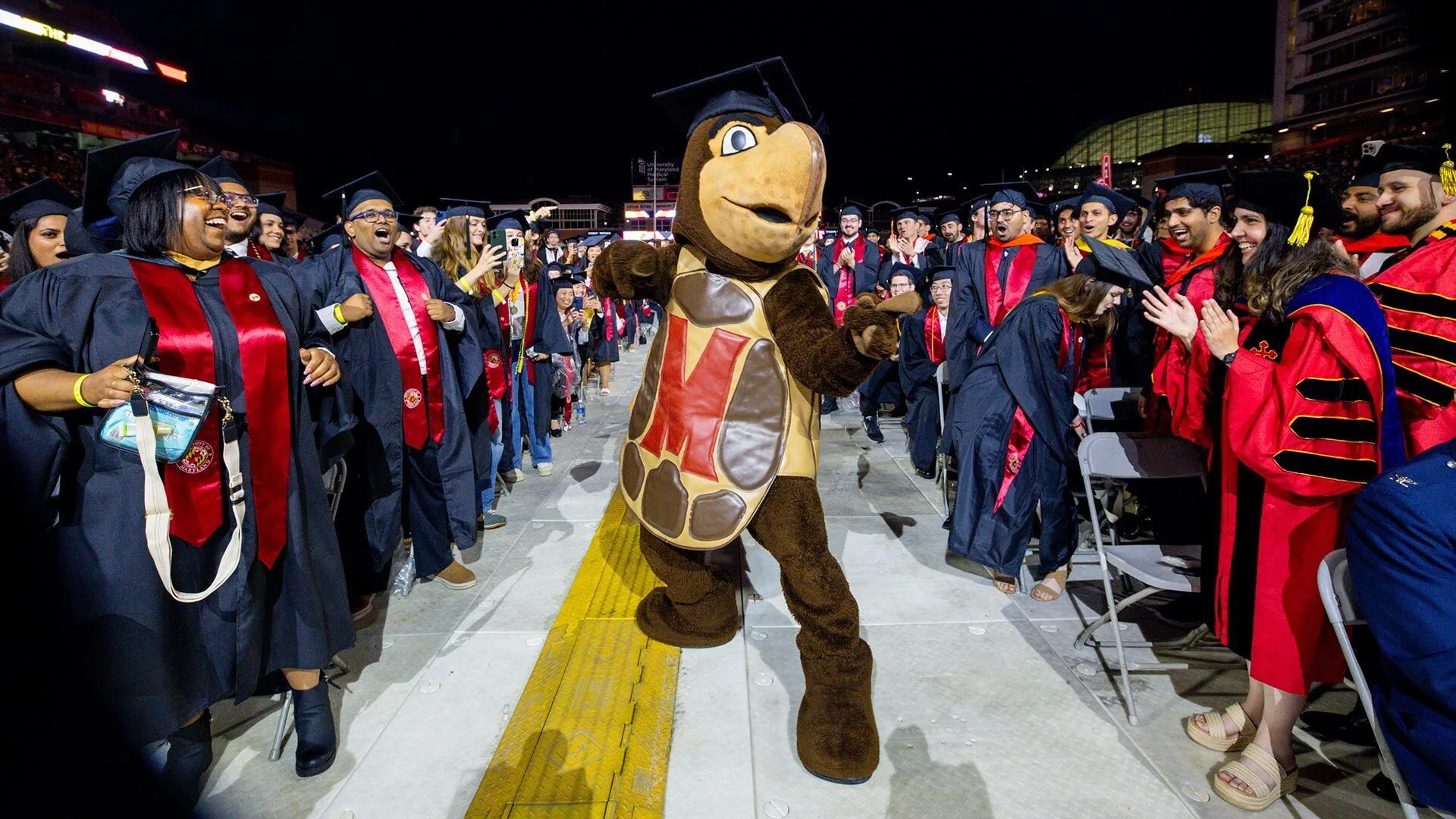 Testudo dances up the aisle wearing regalia