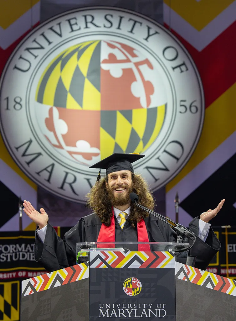 student speaker raises arms at podium