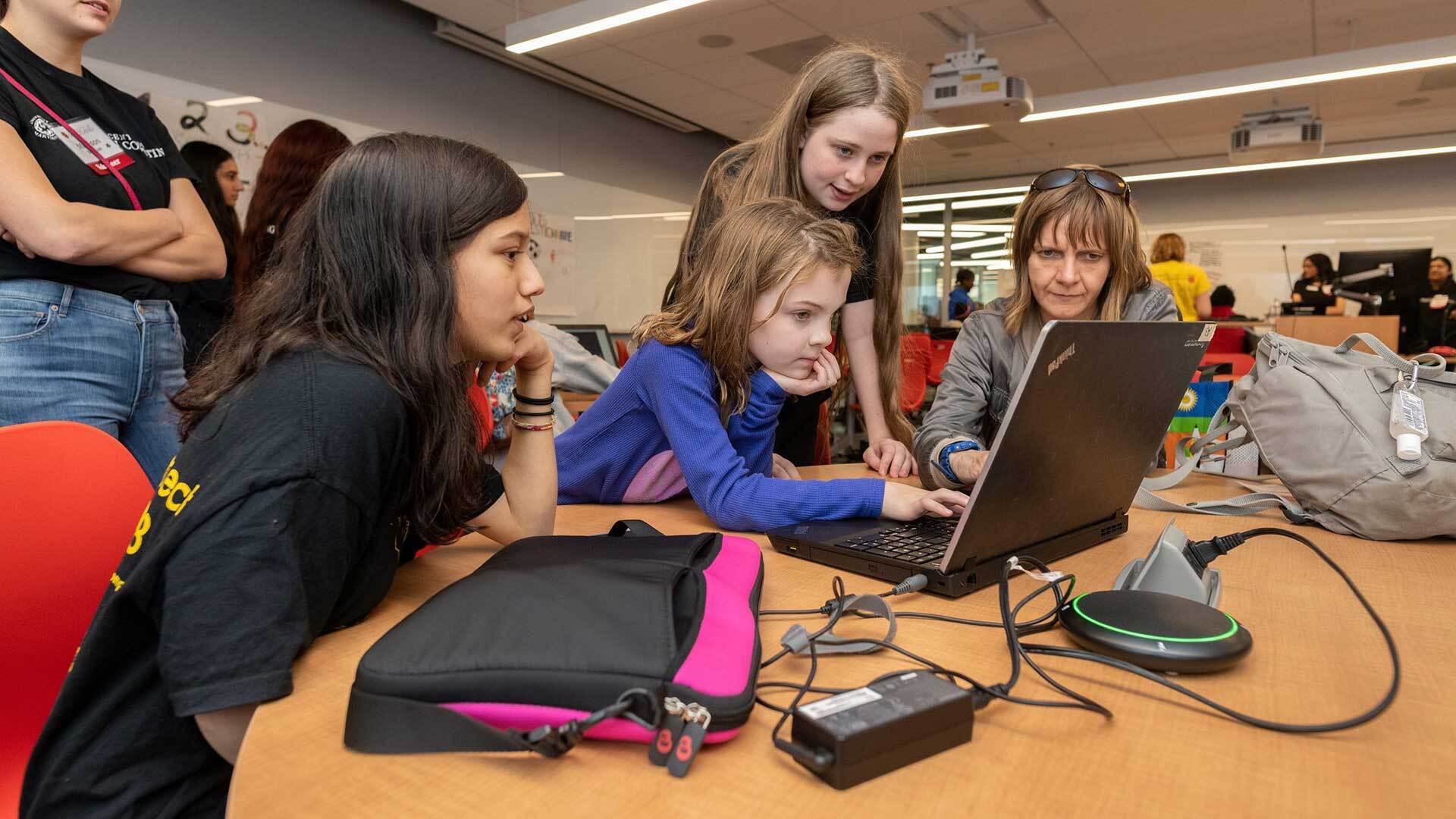 Girls huddle around a laptop