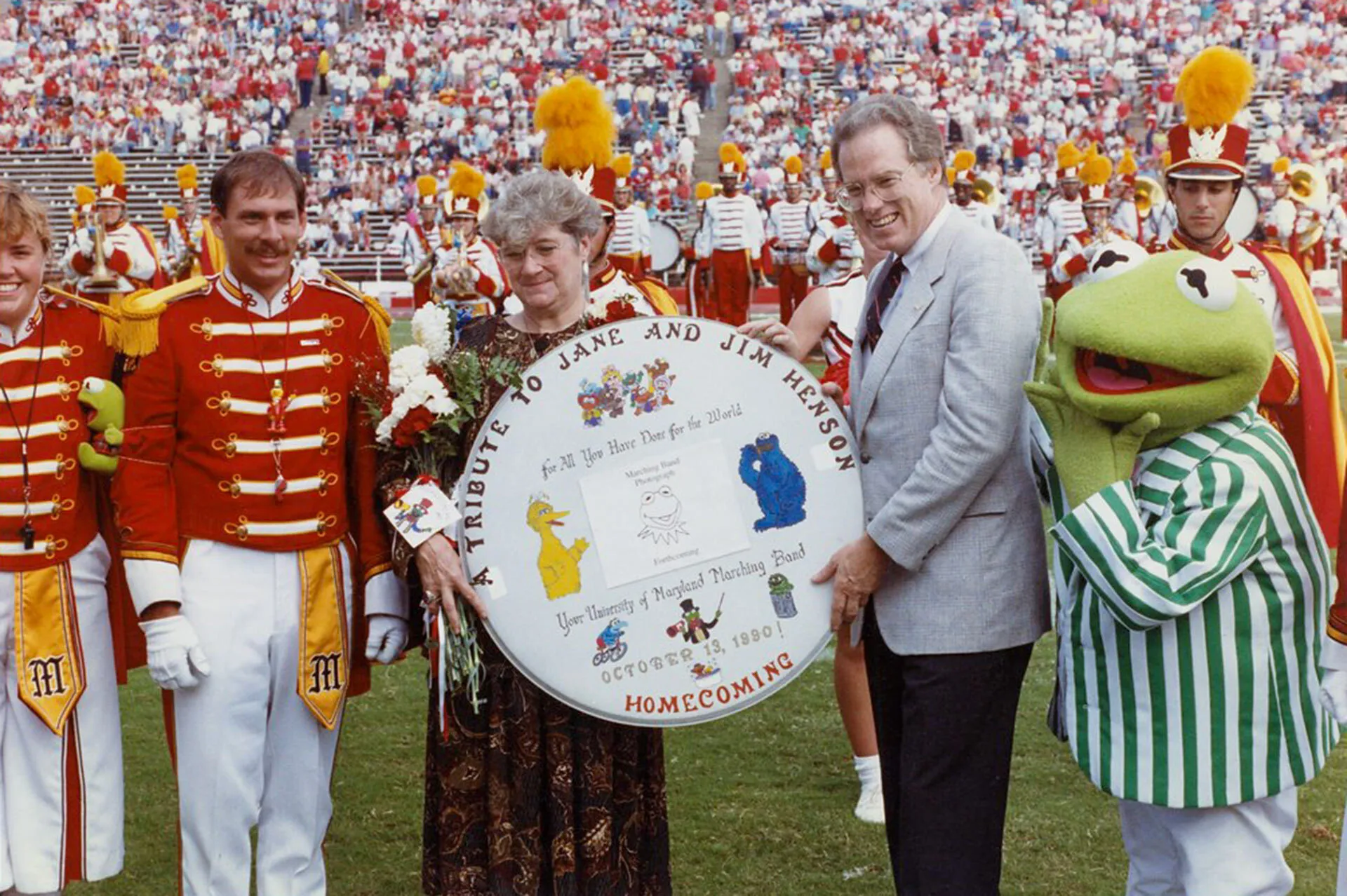 Jane Henson and Brit Kirwan hold a tribute to Jim Henson with marching band members and a life-size Kermit the Frog looking on