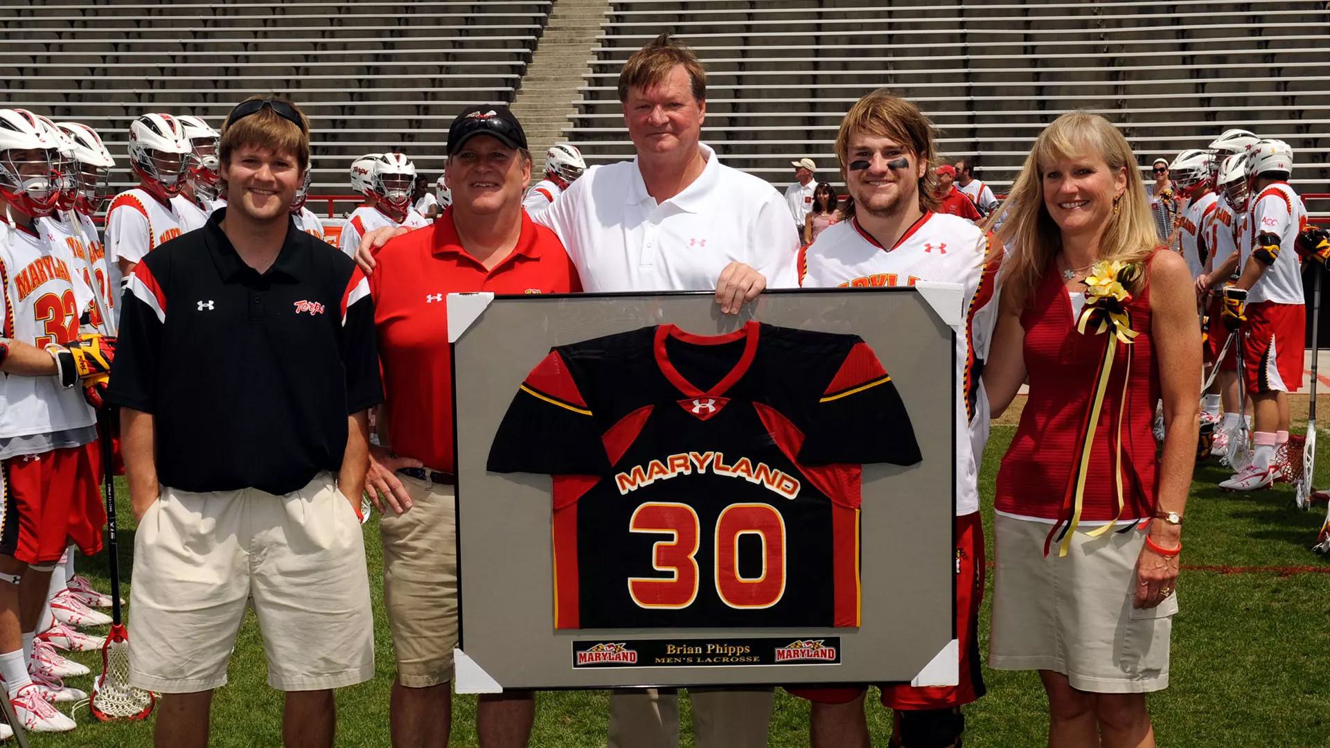 player, family and coach pose with framed jersey