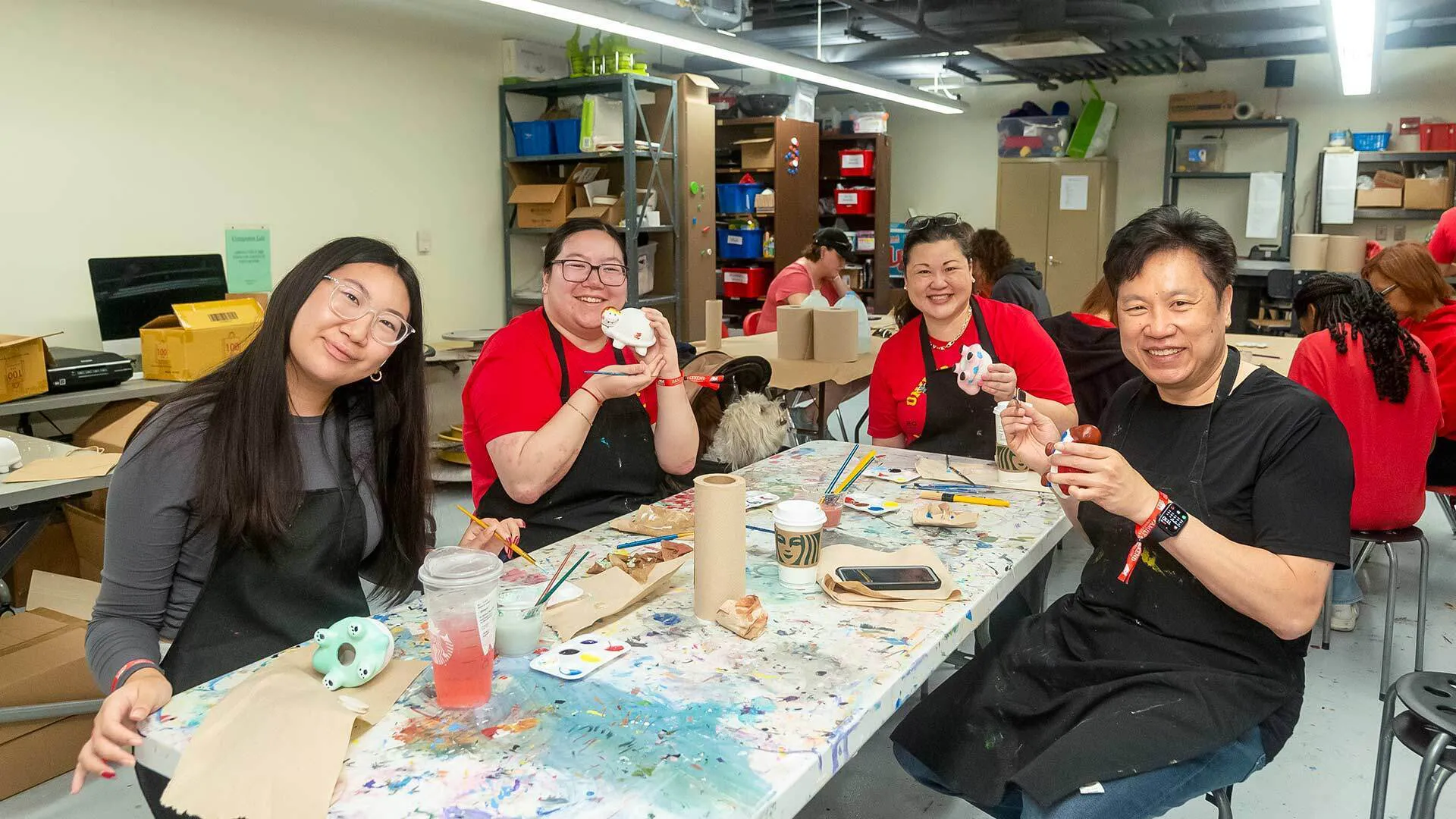 four members of a family paint tiny white turtles in an art studio