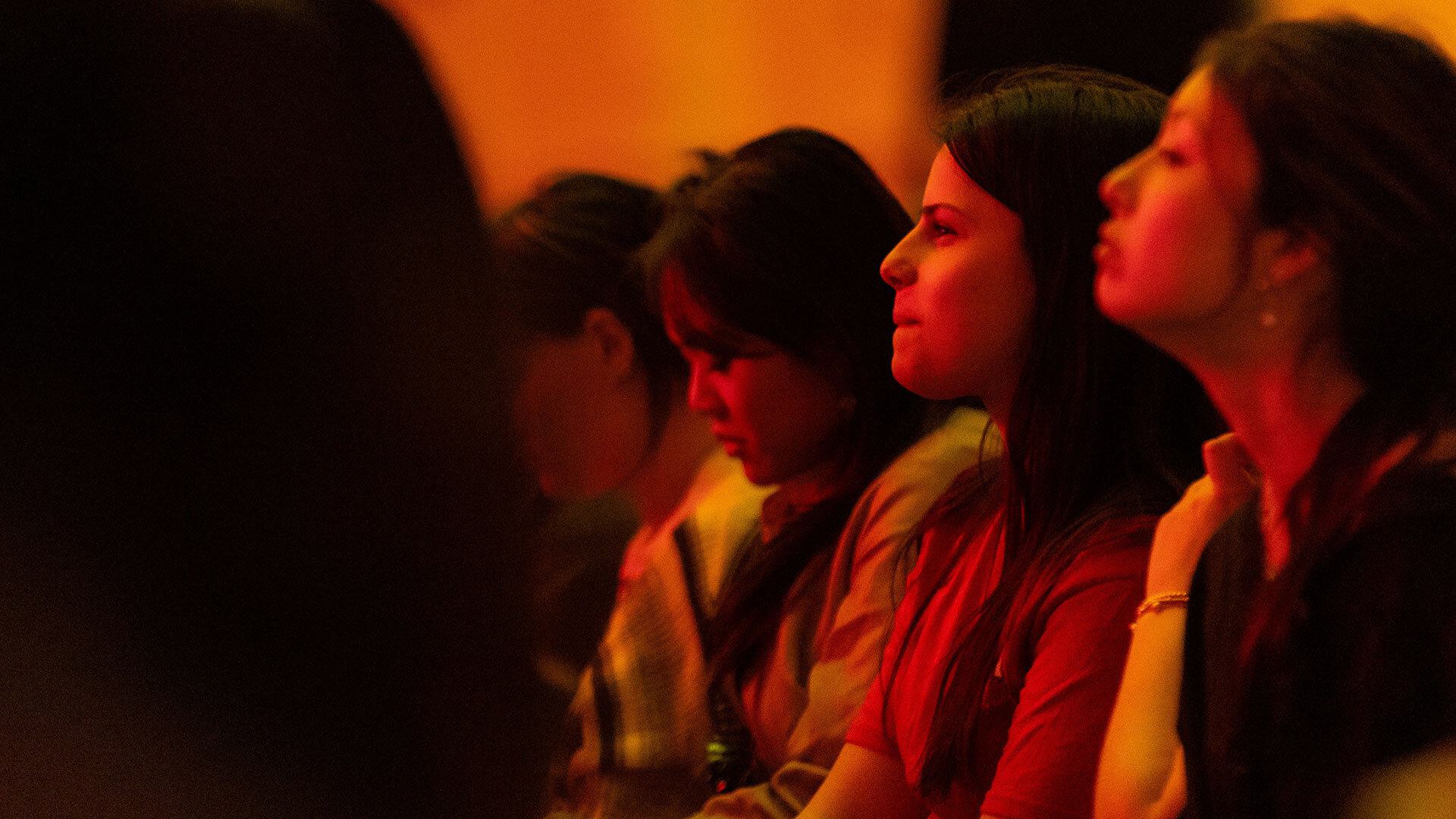 women sit in a theater watching something in front of them